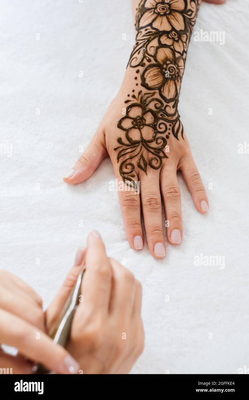 Top view art henné tatuaggio su mani femminili. Master artista che disegna mehndi arabo per sposa prima del matrimonio. Primo piano, vista dall'alto. Design floreale. Cono Foto Stock