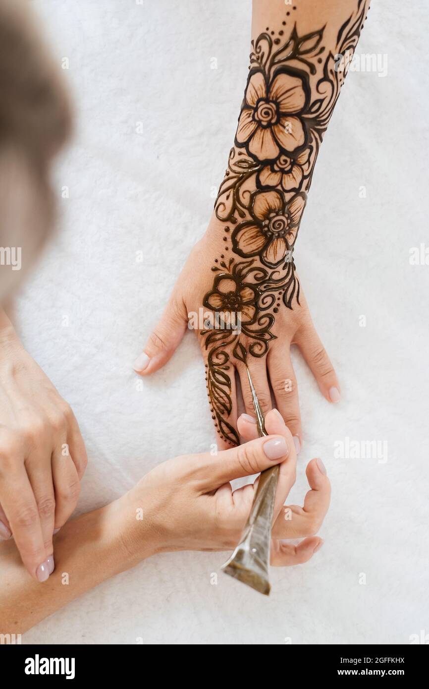 Artista che applica il tatuaggio henné sulle mani delle donne. Il Mehndi è un'arte decorativa indiana tradizionale, a mano con mehendi floreali. Disegno di bellezza per matrimoni e. Foto Stock