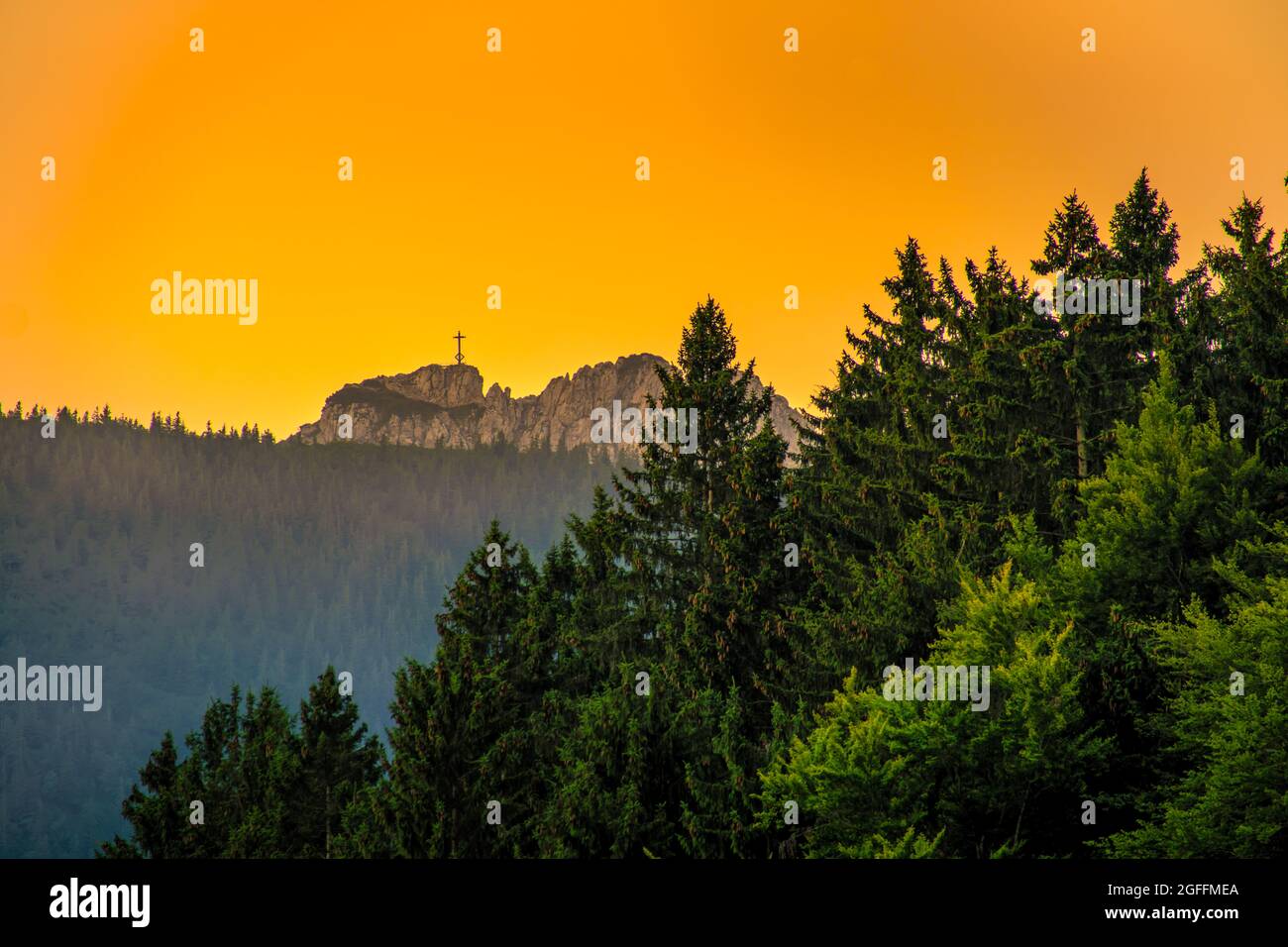 Vista presso la destinazione escursionistica a Kampenwand attraversare a una meravigliosa luce d'oro da lontano, sulla vetta della montagna alpina. Foto Stock