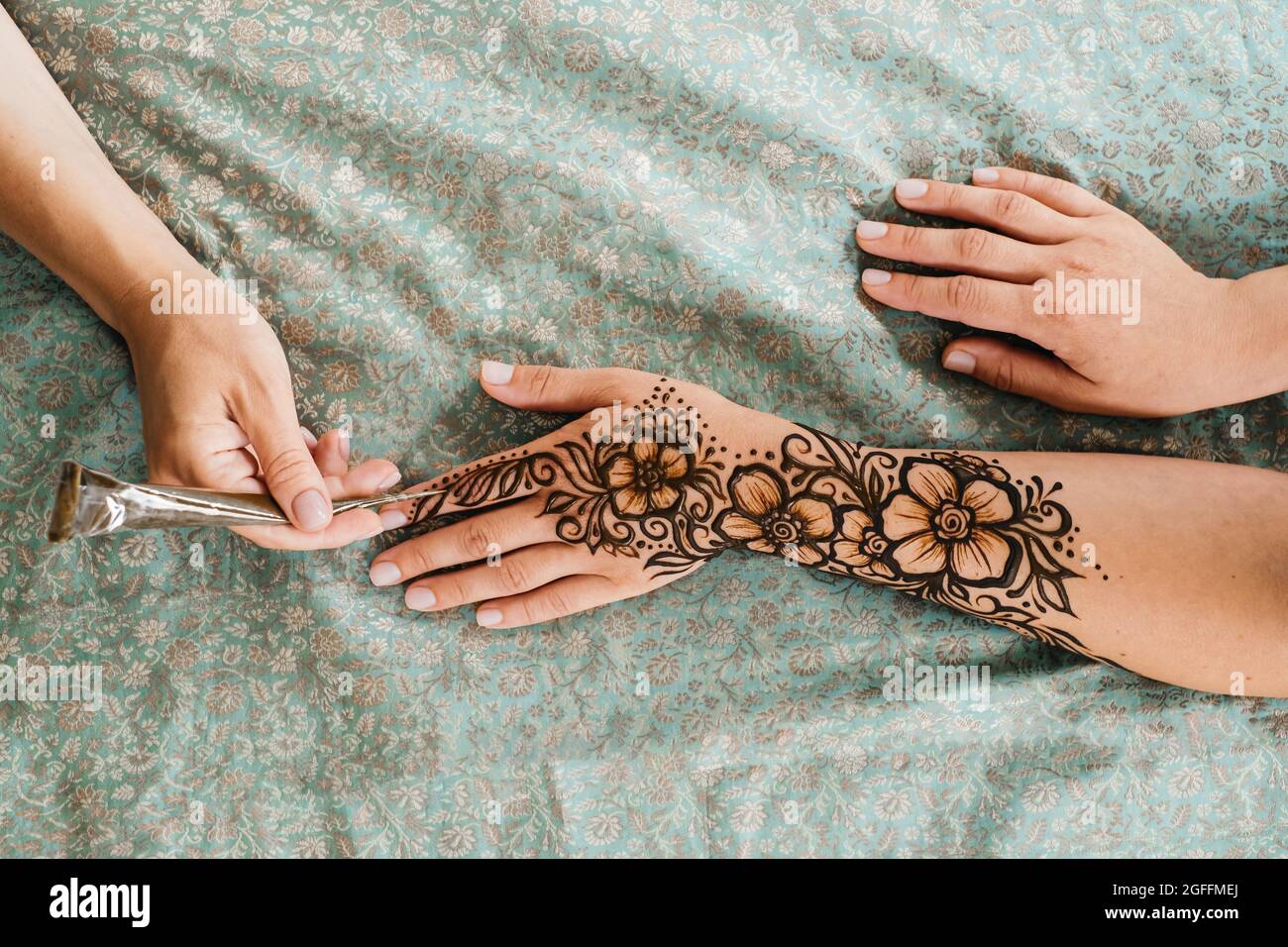 Top view art henné tatuaggio su mani femminili. Master artista che disegna mehndi arabo per sposa prima del matrimonio. Primo piano, vista dall'alto. Design floreale. Cono Foto Stock