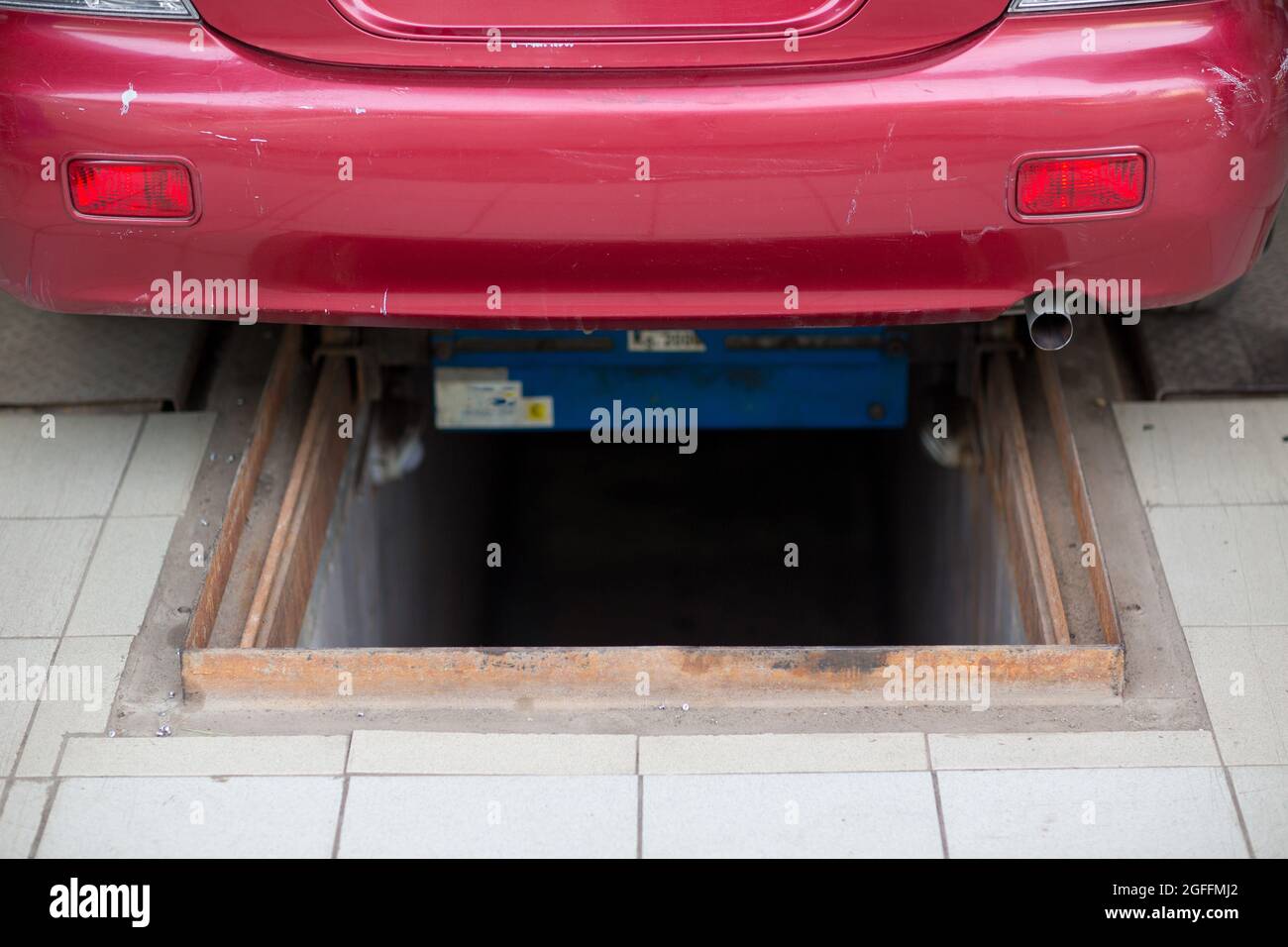 Buca di ispezione nel garage e auto rossa Foto stock - Alamy