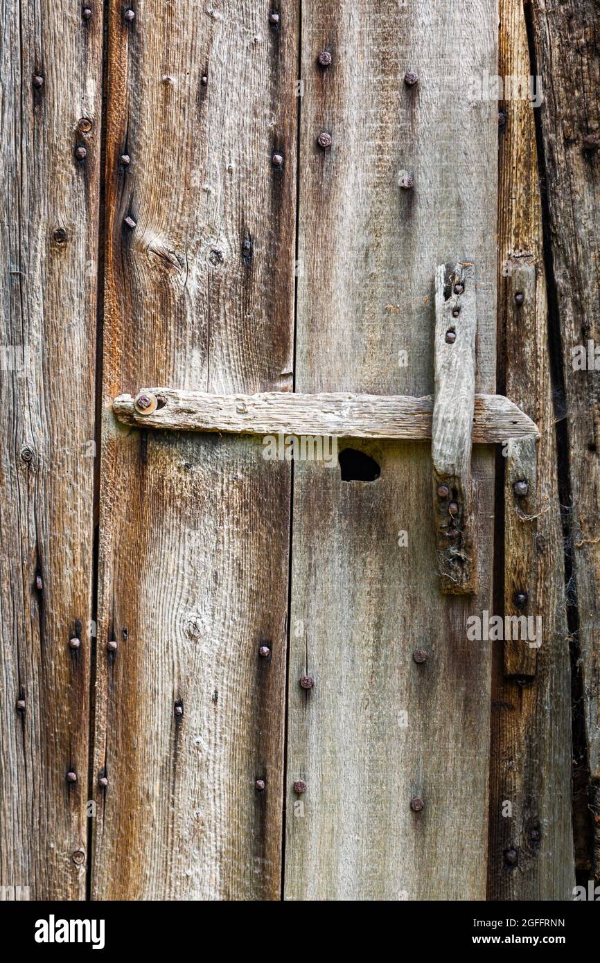 Vecchia porta stabile con intemperie con serratura e maniglia in legno Foto Stock