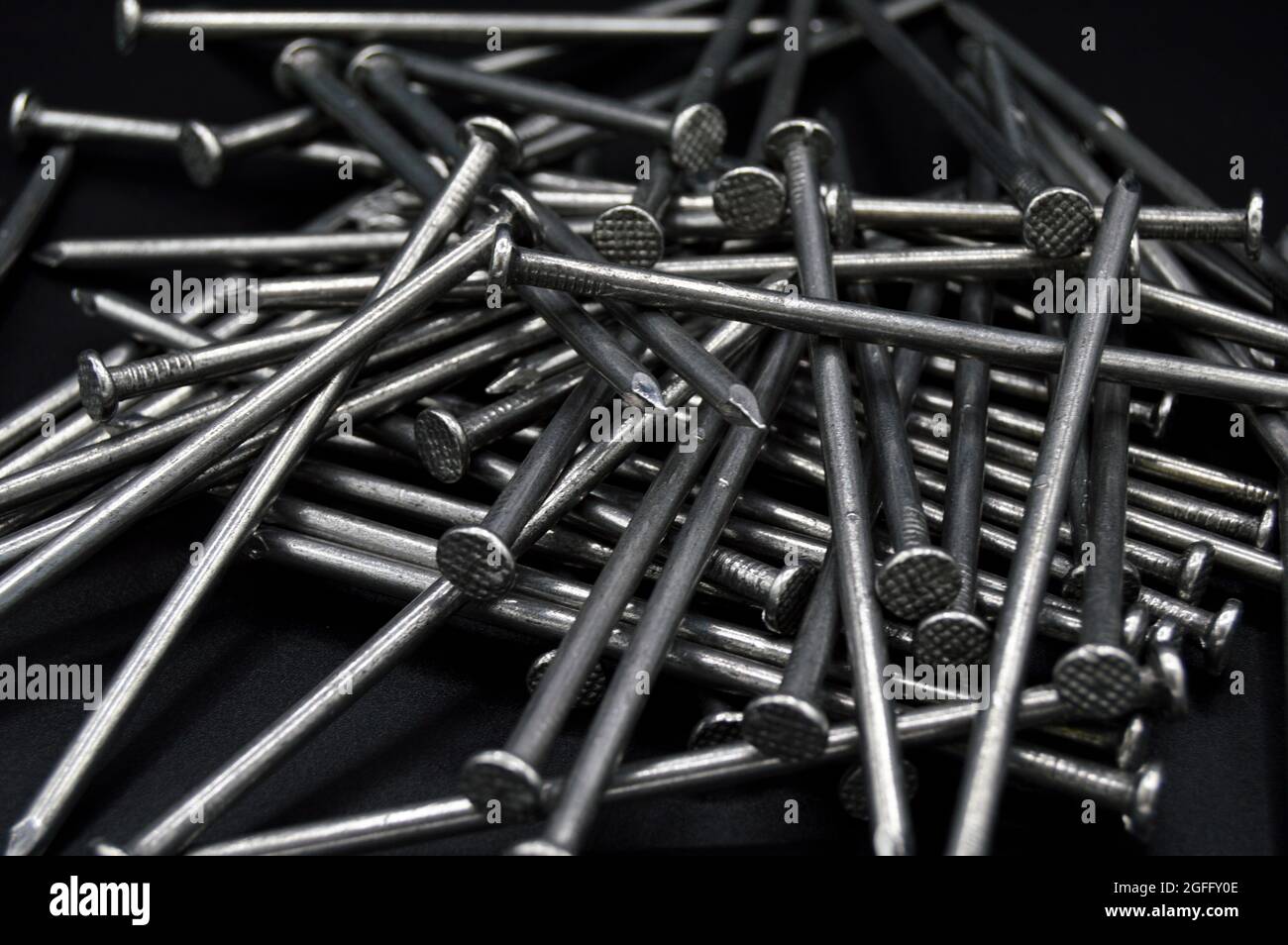 Molti chiodi in ferro da costruzione, parti industriali, isolati su sfondo nero Foto Stock