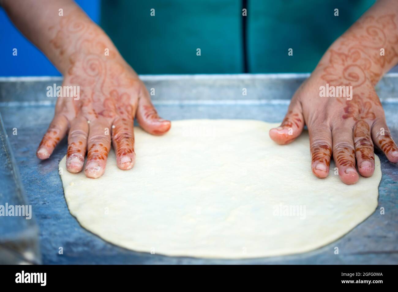 Donna con tatuaggi all'henné sulle mani per preparare pancake. Msemen pasta di pane piatto rotonda preparata sul grill, Marrakech, Marocco Essaouira, Marocco Foto Stock