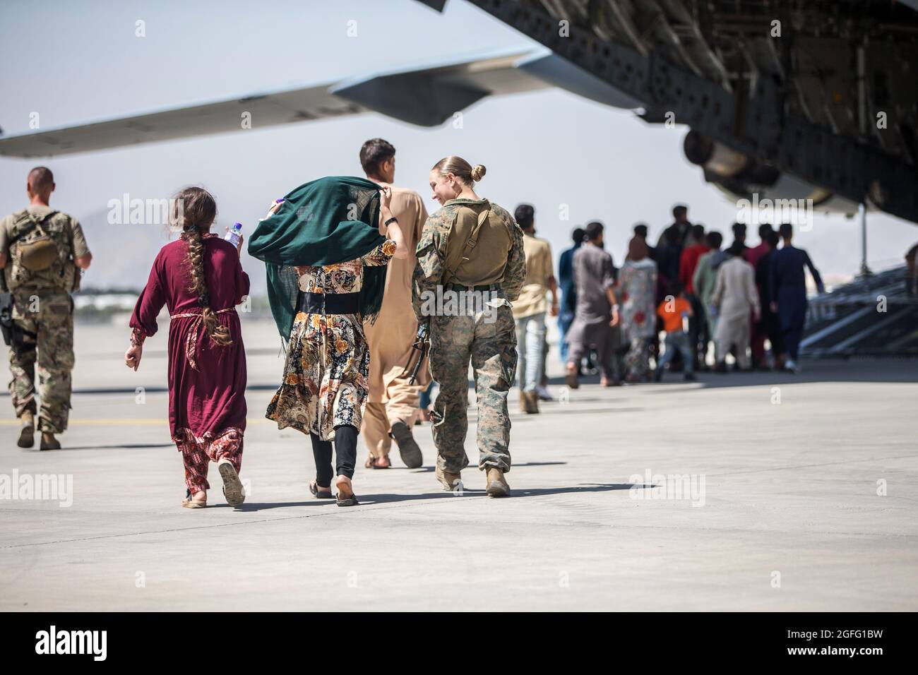 Una Marina degli Stati Uniti con la 24a unità Marine Expeditionary (MEU) cammina con i bambini durante un'evacuazione all'Aeroporto Internazionale Hamid Karzai, Kabul, Afghanistan, 24 agosto 2021. I membri del servizio USA stanno assistendo il Dipartimento di Stato degli Stati Uniti con un prelievo ordinato di personale designato in Afghanistan. Credito obbligatorio: Samuel Ruiz/US Marine Corps via CNP /MediaPunch Foto Stock