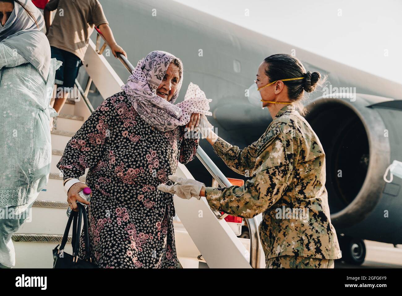 Sigonella, Italia. 22 agosto 2021. Il comandante della Marina degli Stati Uniti, Anna Wood, assiste gli evacuati quando sbarcano da un aereo della forza aerea C-17 Globemaster III degli Stati Uniti dopo l'arrivo alla base aerea navale di Sigonella il 22 agosto 2021 a Sigonella, Italia. NAS Sigonella fornisce alloggio temporaneo per gli evacuati dall'Afghanistan come parte dell'operazione Rifugi Alleati. Credit: Planetpix/Alamy Live News Foto Stock