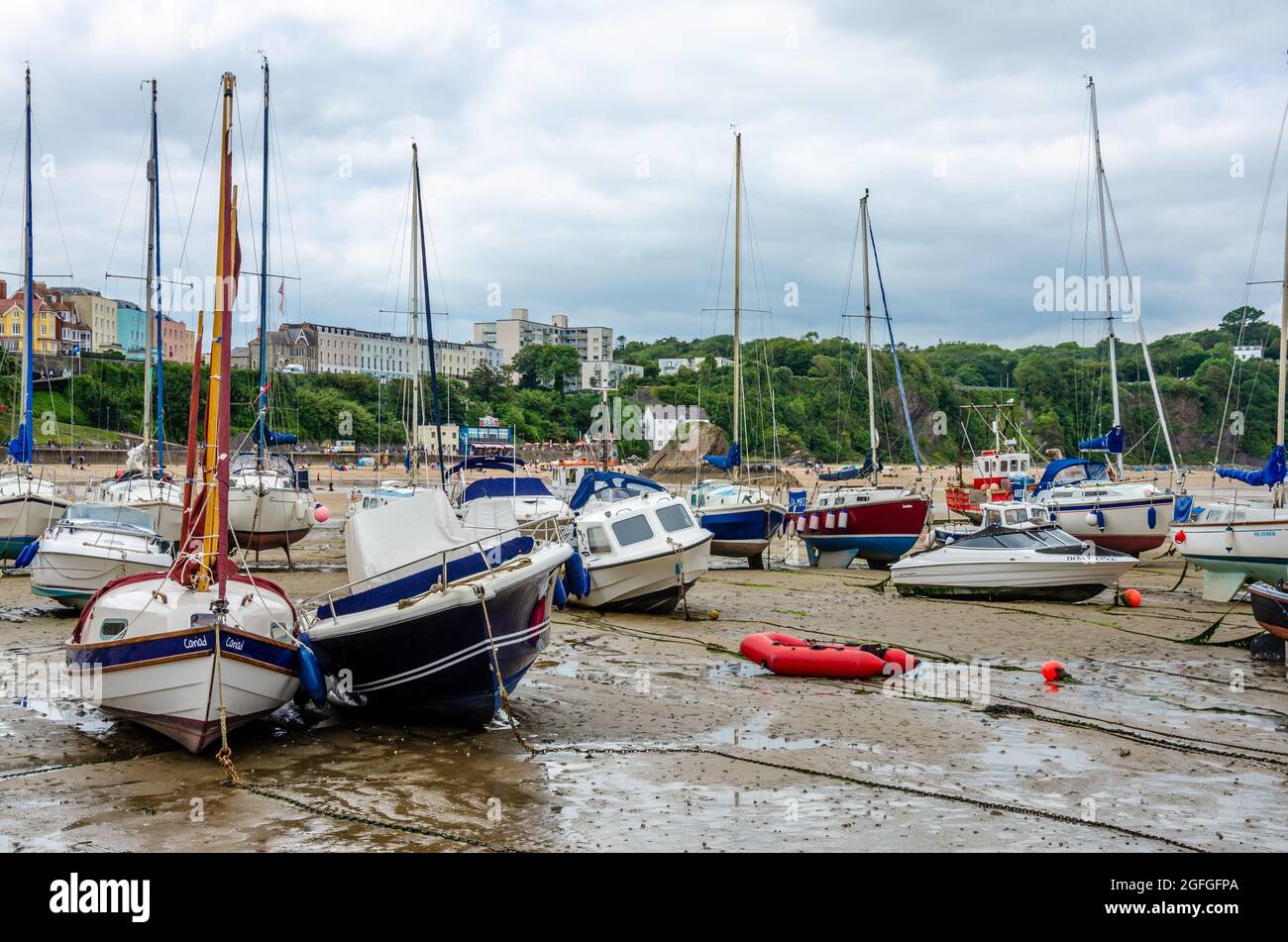 Barche in barca a vela nel porto di Tenby a Pembrokeshire, Galles, con bassa marea. La sabbia è stata rivelata e il mare è completamente fuori, Foto Stock