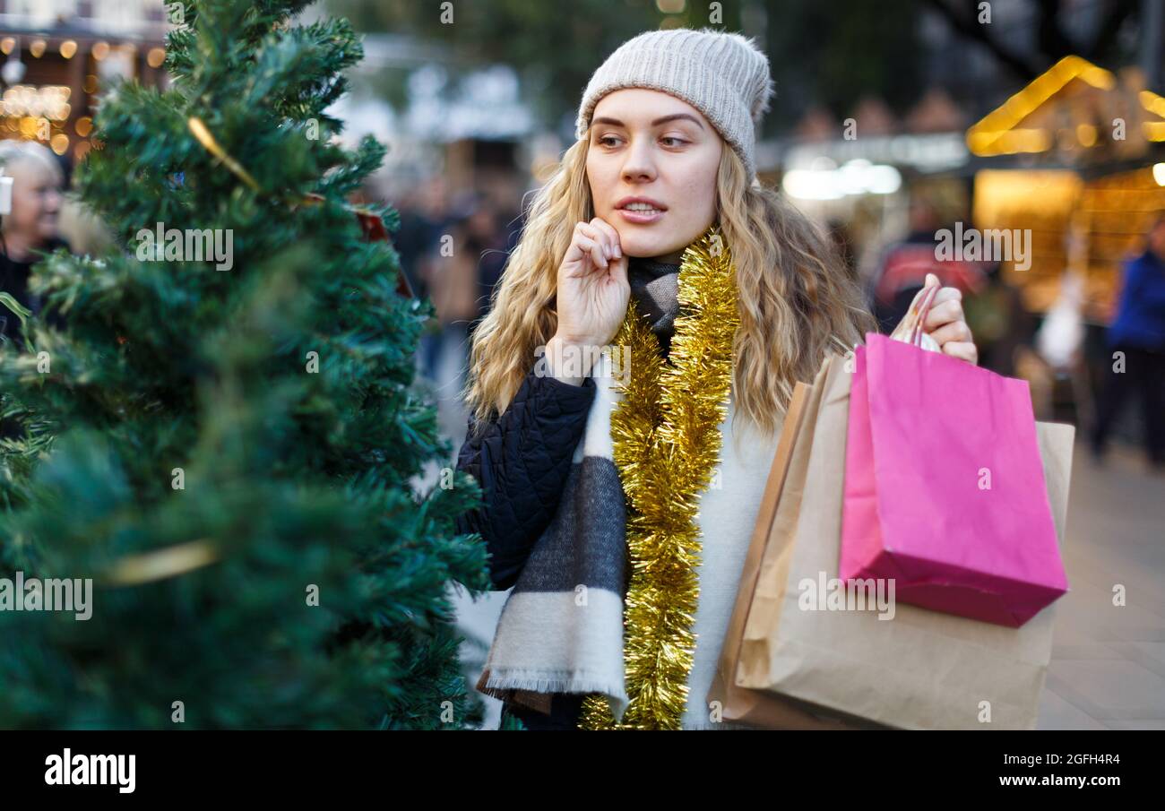Ragazza con i sacchetti di carta che scelgono l'albero di Natale Foto Stock