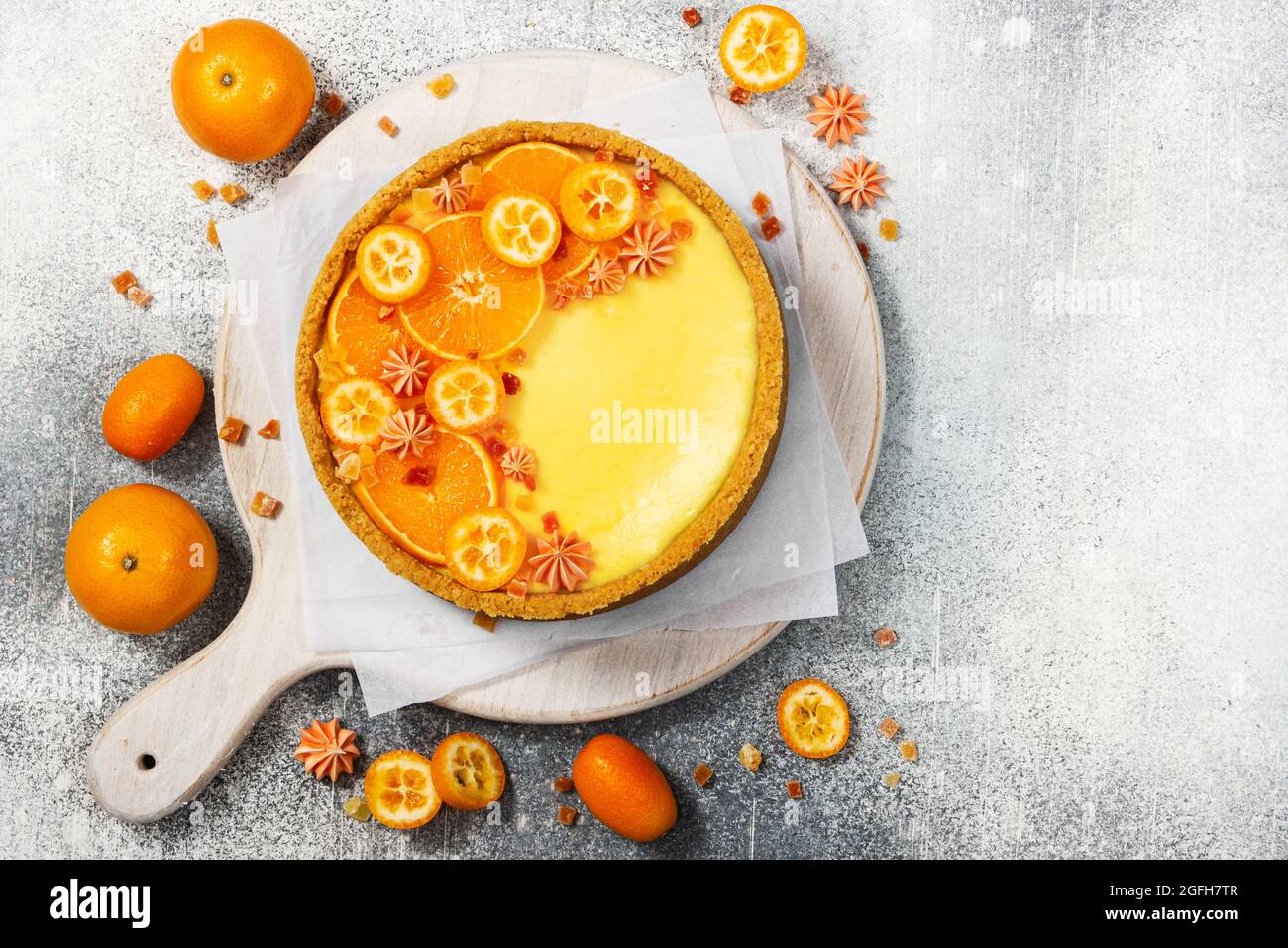 Cheesecake con fette di arancia e kumquat su fondo grigio in pietra. Vista dall'alto. Foto Stock