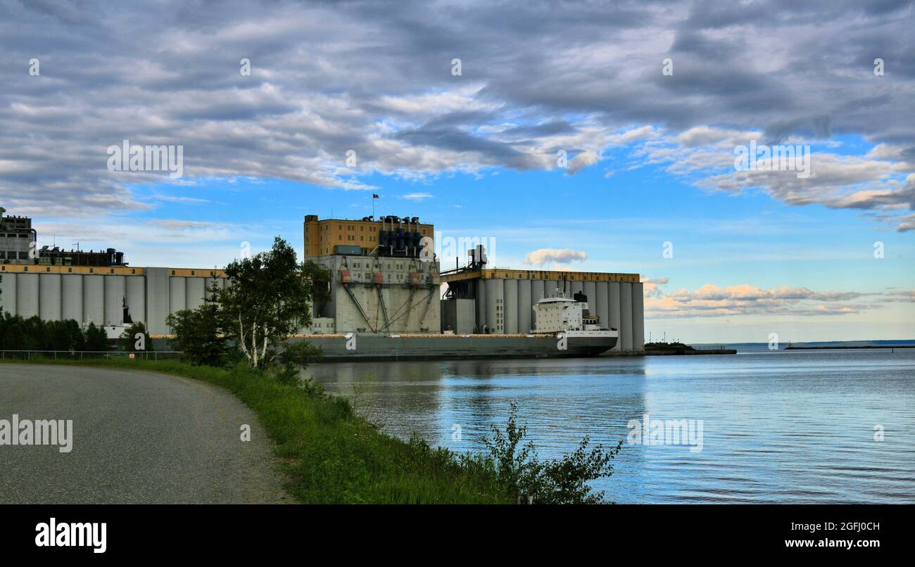 Ascensore secolare di grano siede sul Lago superiore a Thunder Bay Ontario, Canada, mentre un freighter arriva a raccogliere grano in un giorno di primavera. Foto Stock