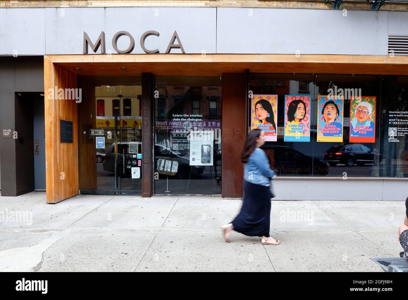 Una persona cammina accanto al Museo dei Cinesi in America, un museo di storia a Manhattan Chinatown, con i poster di odio Stop Asian nella finestra. Ago 21, 2021 Foto Stock