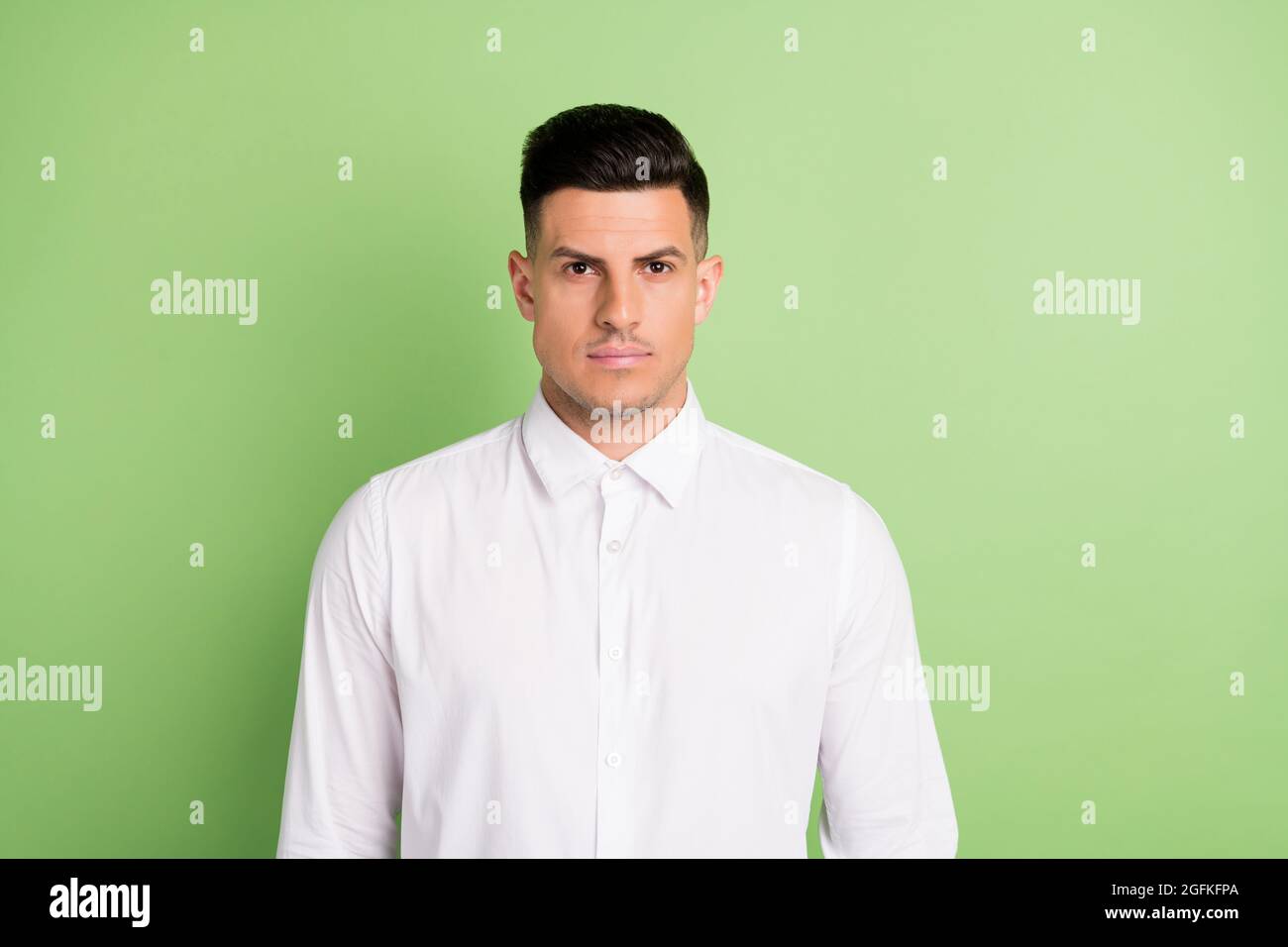 Foto di sicuro serio giovane Signore indossare camicia bianca in piedi diritto isolato sfondo di colore verde Foto Stock