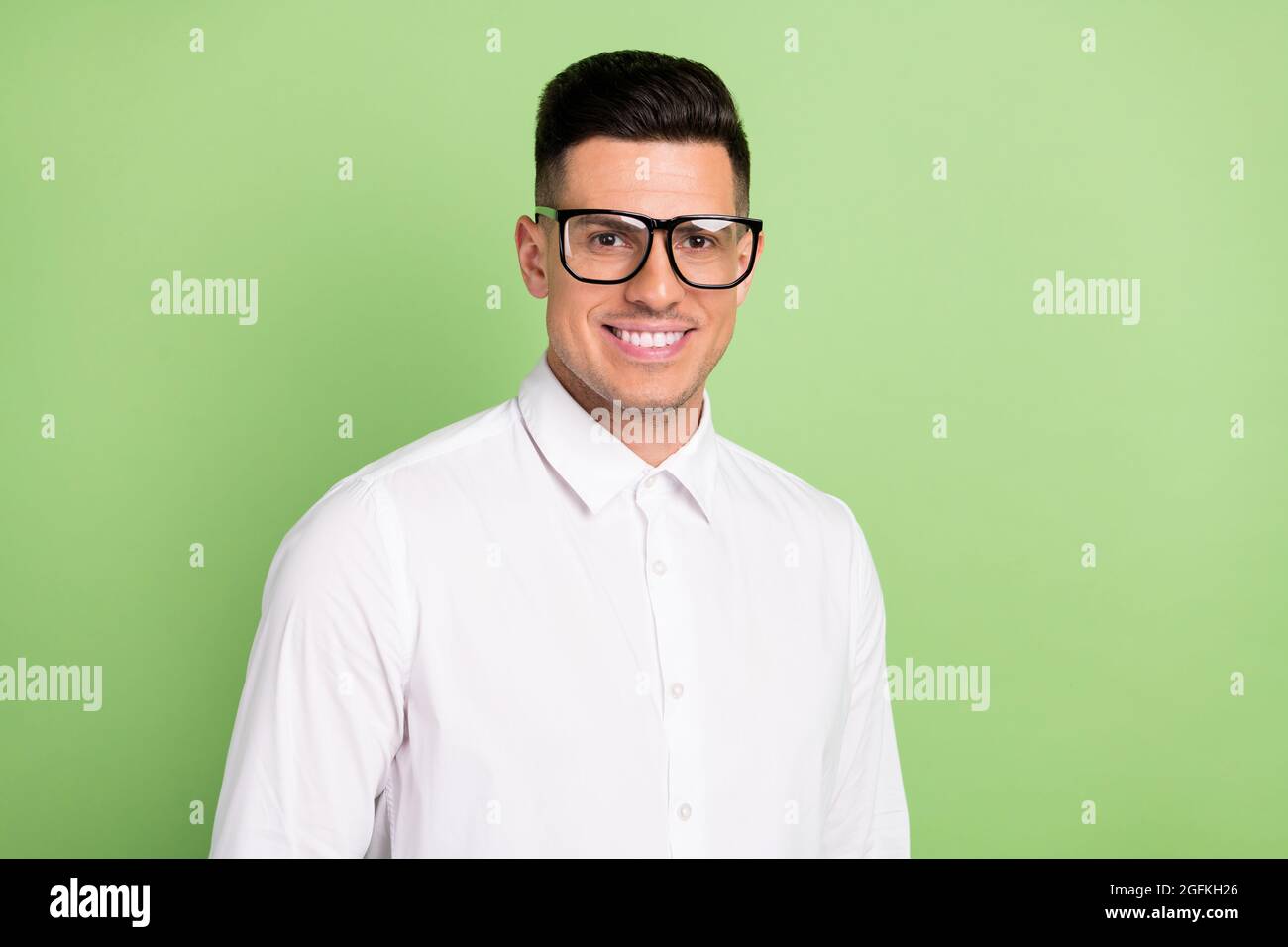 Foto di simpatico giovane uomo indossare occhiali da maglietta bianco sorridente isolato sfondo di colore verde Foto Stock