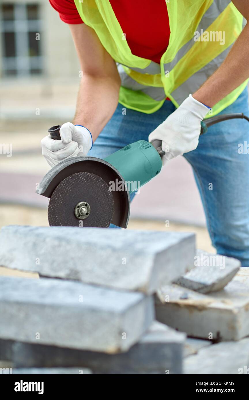 Operatore esperto in guanti di cotone bianco per la preparazione di materiali da costruzione per la pavimentazione Foto Stock