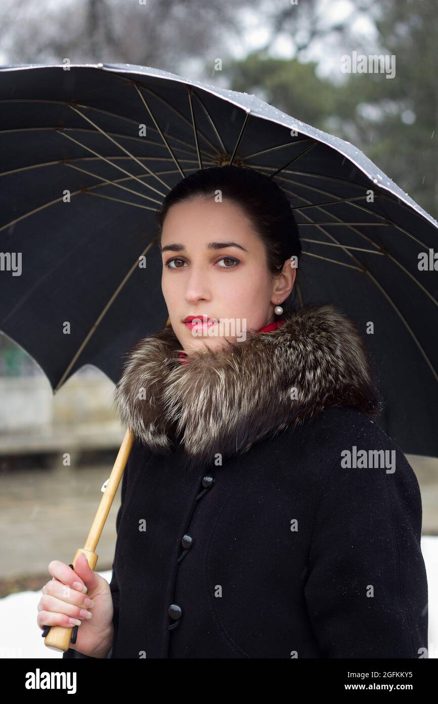 Ritratto di bella ragazza giovane tiene ombrello nel parco invernale Foto Stock