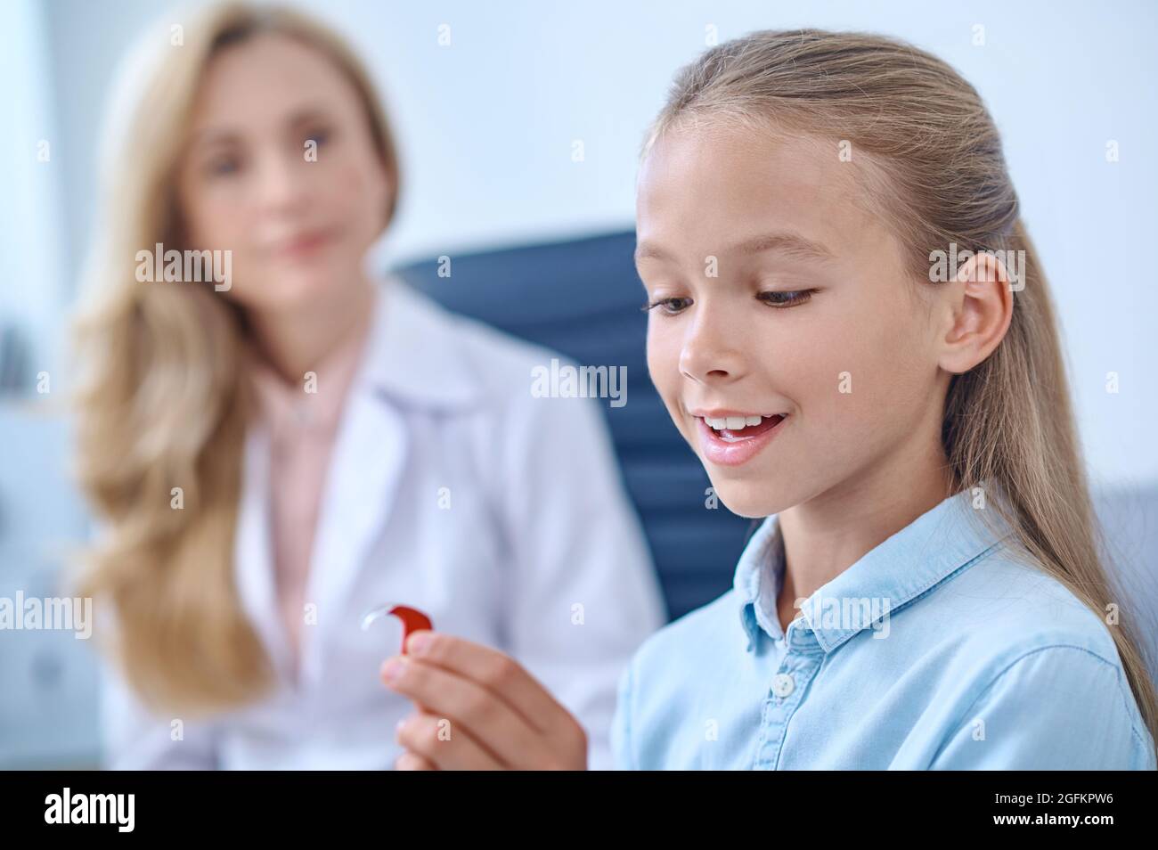 Ragazza felice età della scuola che ammira gli apparecchi acustici Foto Stock