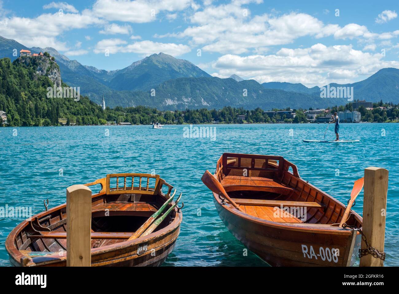 Barca da piacere e acqua limpida con Castello e montagne sullo sfondo Foto Stock