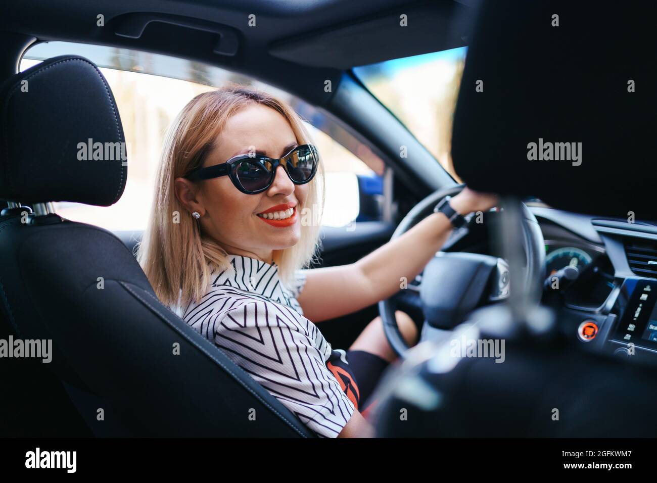 Donna sicura e bella in occhiali da sole. Vista posteriore di una giovane  donna attraente in un abbigliamento casual alla guida di un'auto Foto stock  - Alamy