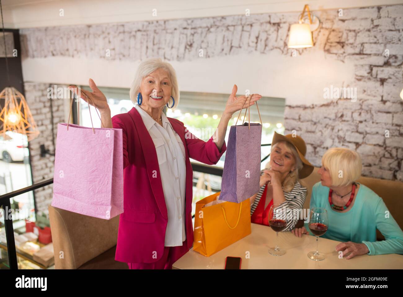Donne anziane allegre con i sacchetti di shopping che osservano felice Foto Stock