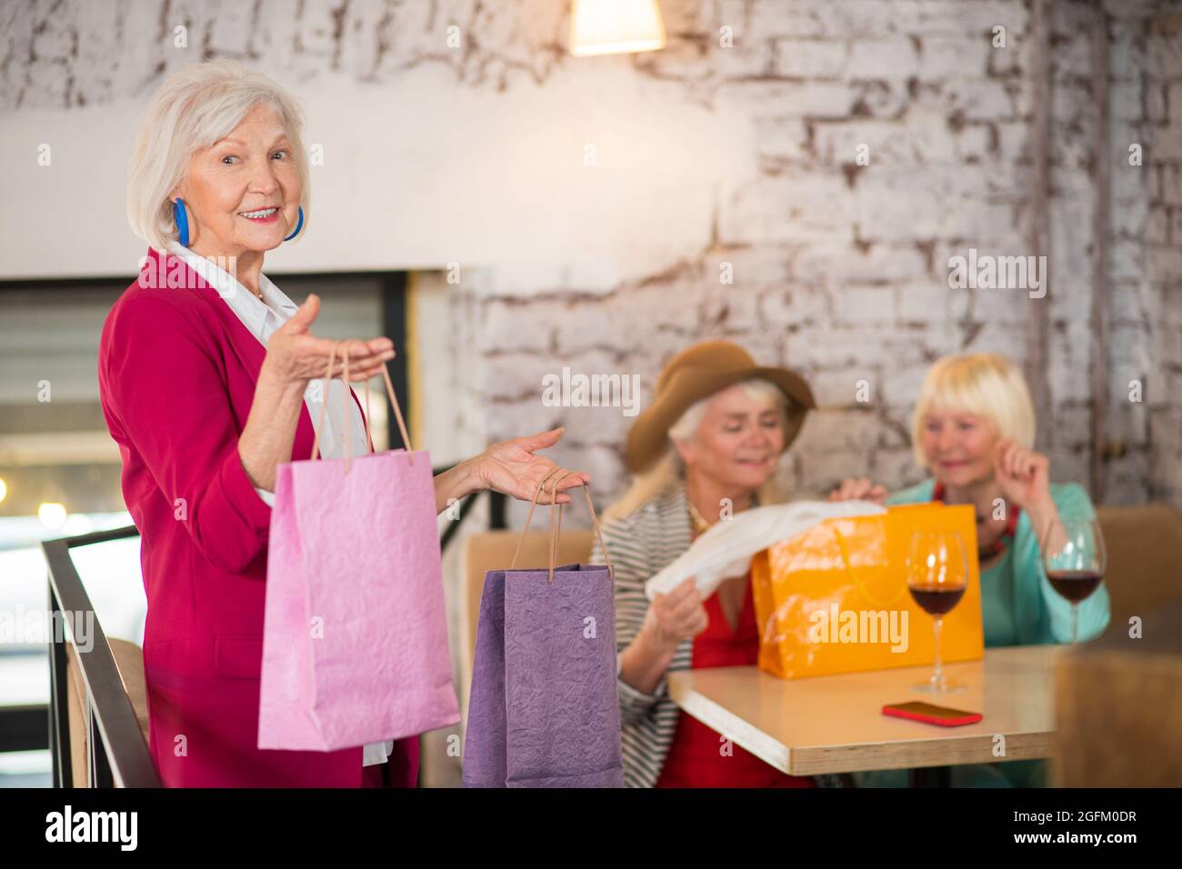 Donne anziane allegre con i sacchetti di shopping che osservano felice Foto Stock