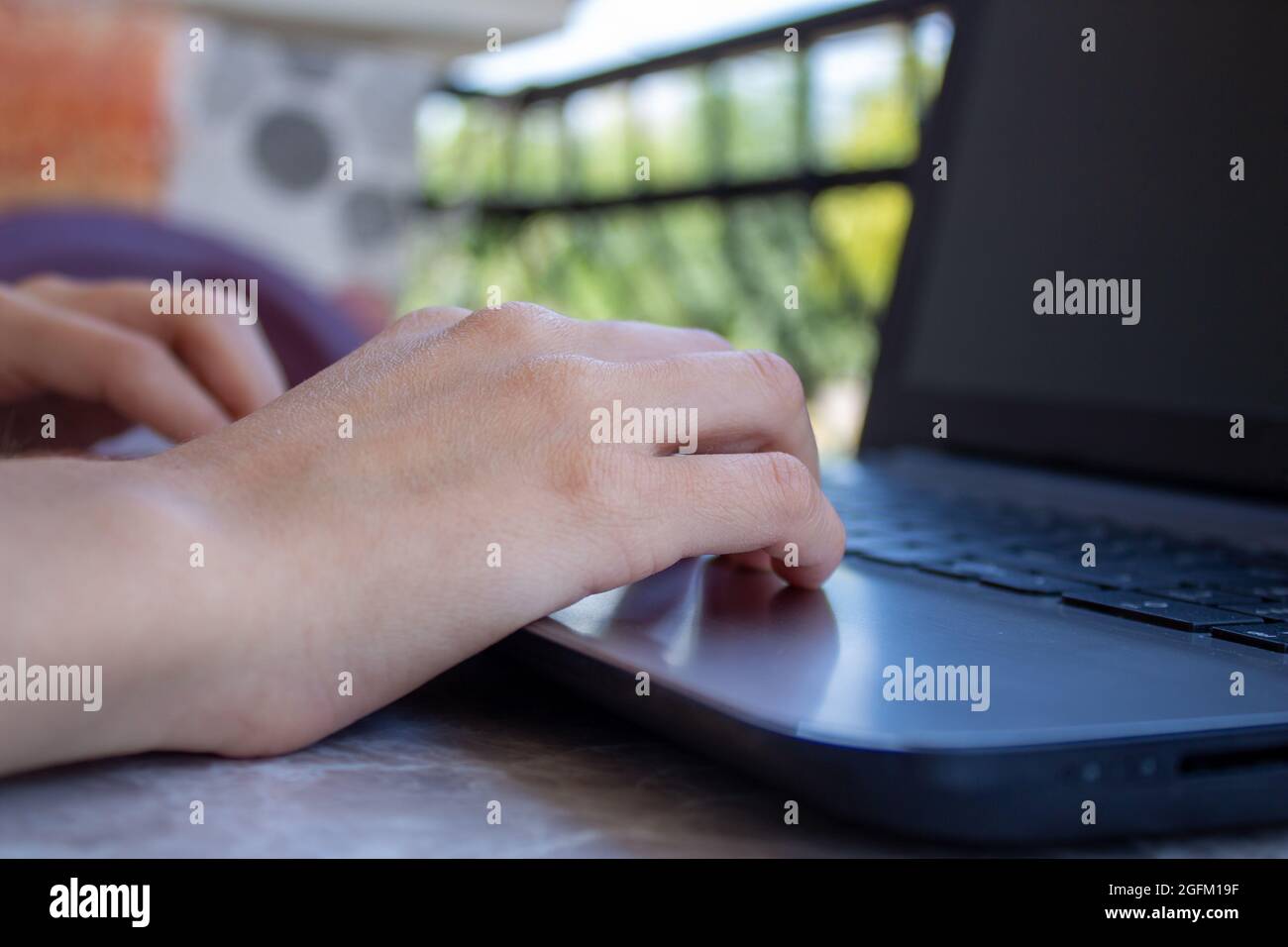 Donna freelance che lavora sul balcone della sua casa utilizzando il laptop. Donna seduta su sedia e utilizzando il computer all'aperto. Foto Stock