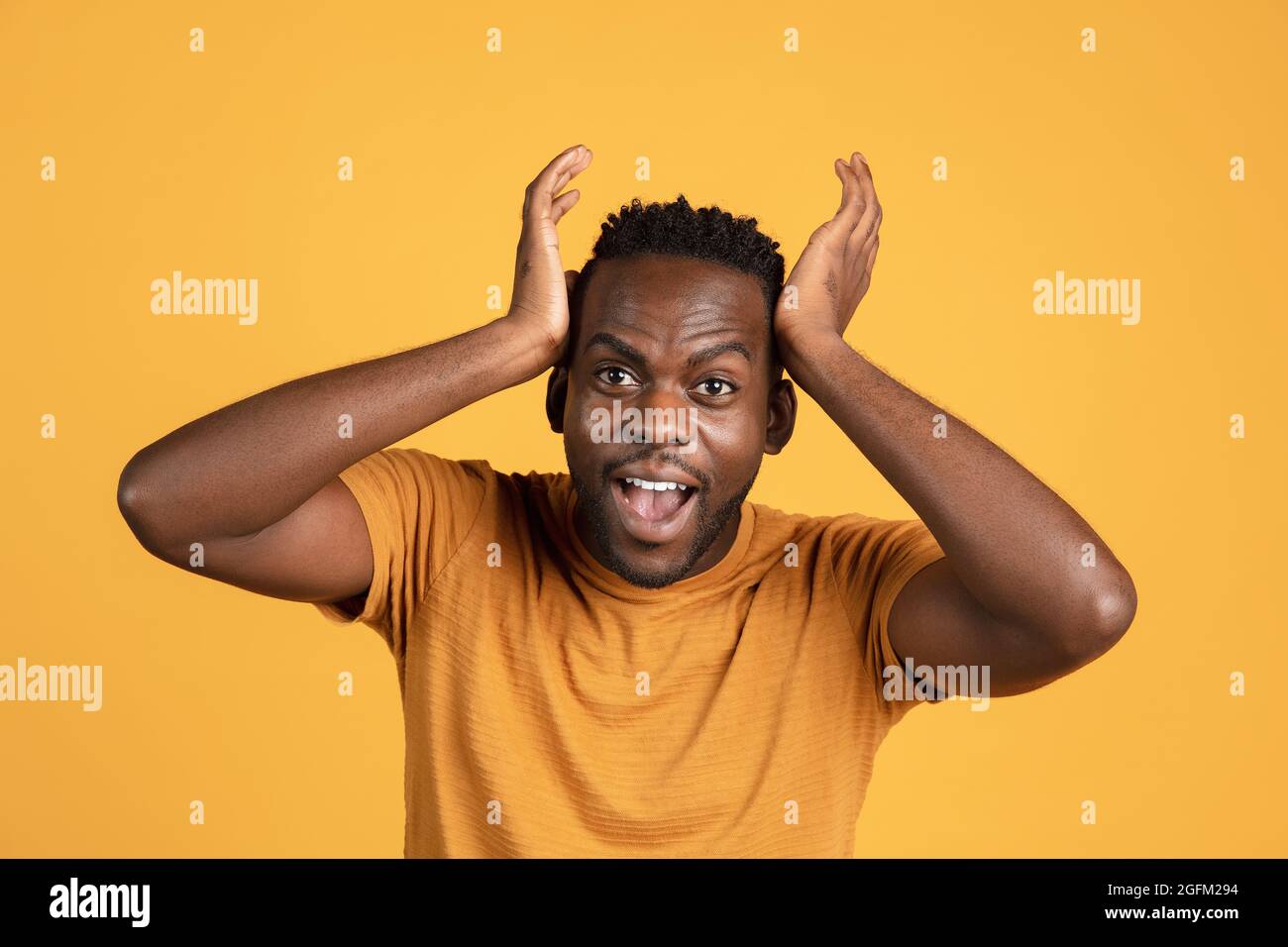 Ritratto di giovane africano in abiti casual isolato su sfondo giallo studio. Concetto di emozioni umane, espressione facciale, gioventù Foto Stock