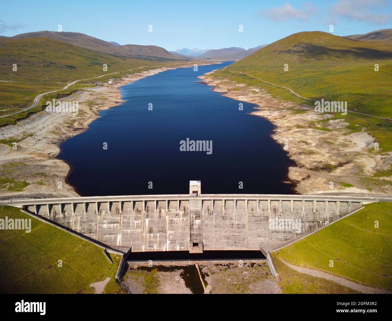 Garve ,Scozia, Regno Unito. 26 agosto 2021. Questa fotografia del drone mostra il livello dell'acqua in Glascarnoch Loch è basso dopo molti mesi relativamente asciutti con pioggia bassa. Glascarnoch Dam fa parte dello schema idroelettrico Conon di SSE. Il tempo caldo e secco continuo in agosto non farà nulla per aumentare i livelli d'acqua nel lago. Iain Masterton/Alamy Live News. Foto Stock
