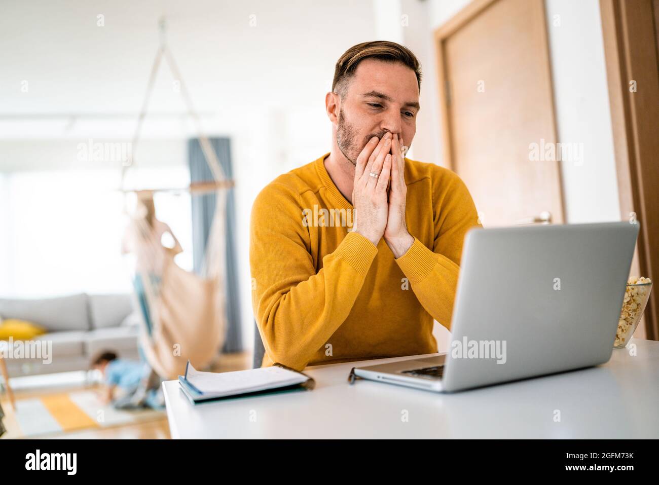 Sconvolto giovane uomo conta budget familiare su laptop Foto Stock