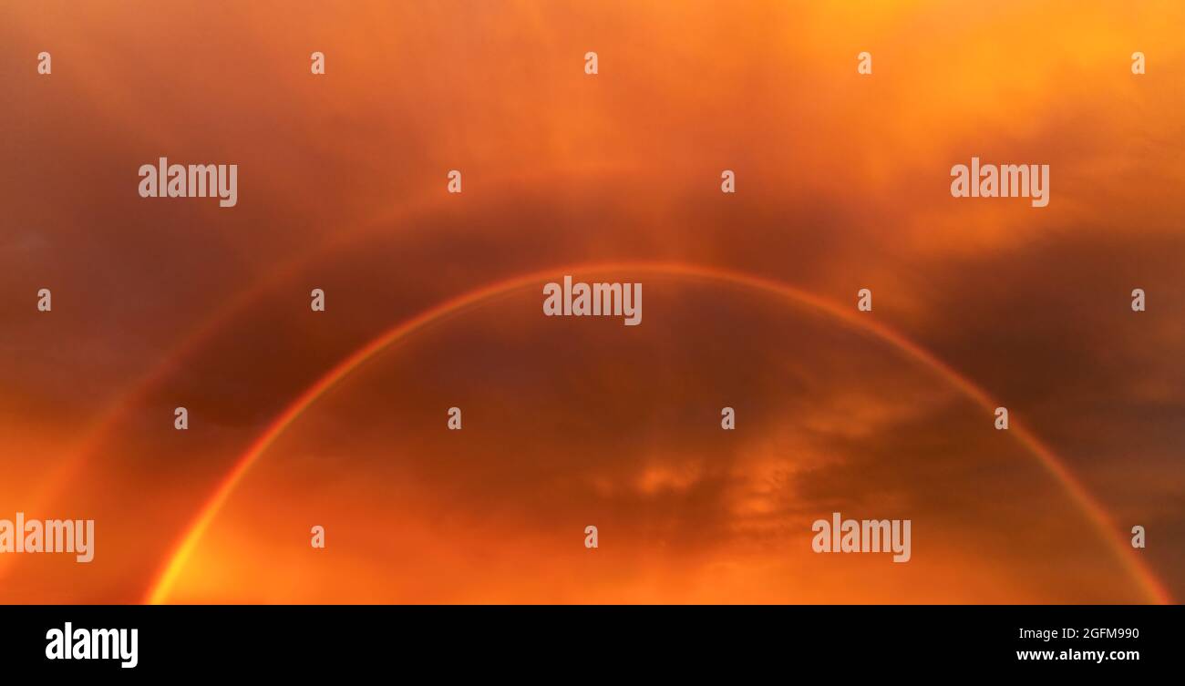 Drammatico cielo di colore arancione con un doppio arcobaleno rosso al tramonto, gioco celeste di colori dopo la pioggia, un fenomeno meteorologico, la Germania Foto Stock