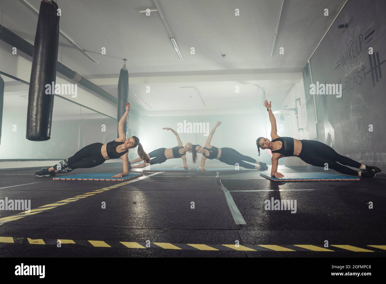 Donne in bianco e nero abbigliamento sportivo su un vero gruppo corpo combattimento allenamento in palestra treno per combattere, kickboxing con un allenatore. Foto Stock