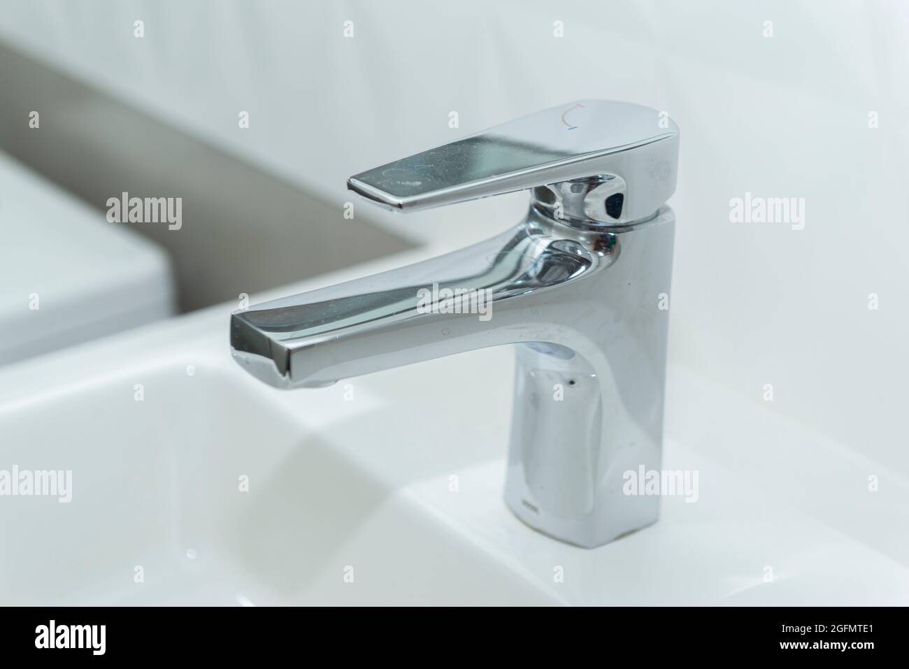 Lavello rettangolare in marmo bianco con moderno bacino overlay e rubinetto in acciaio inossidabile lucido. Aprire l'acqua di sgushing del rubinetto. Foto Stock
