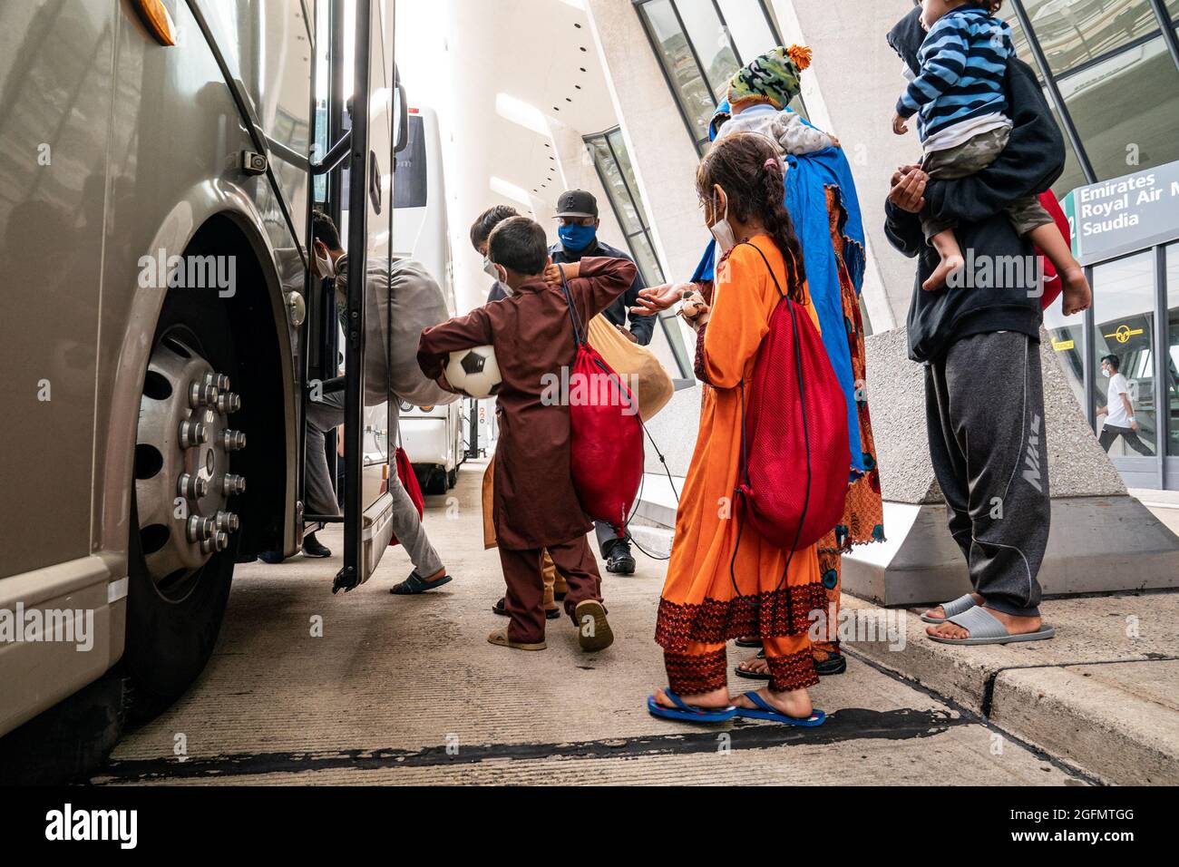 Dulles, Stati Uniti. 26 agosto 2021. I rifugiati evacuati da Kabul, Afghanistan, aspettano di salire a bordo di un autobus che li porterà in un centro di lavorazione dei rifugiati presso l'aeroporto internazionale Dulles di Dulles, Virginia, giovedì 26 agosto 2021. Secondo il Dipartimento della Difesa degli Stati Uniti, da ieri, circa 88,000 sono partiti in sicurezza dall'Afghanistan, con cinque voli che trasportano 1,200 passeggeri che atterrano all'Aeroporto Internazionale di Washington Dulles. Foto di Ken Cedeno/UPI Credit: UPI/Alamy Live News Foto Stock