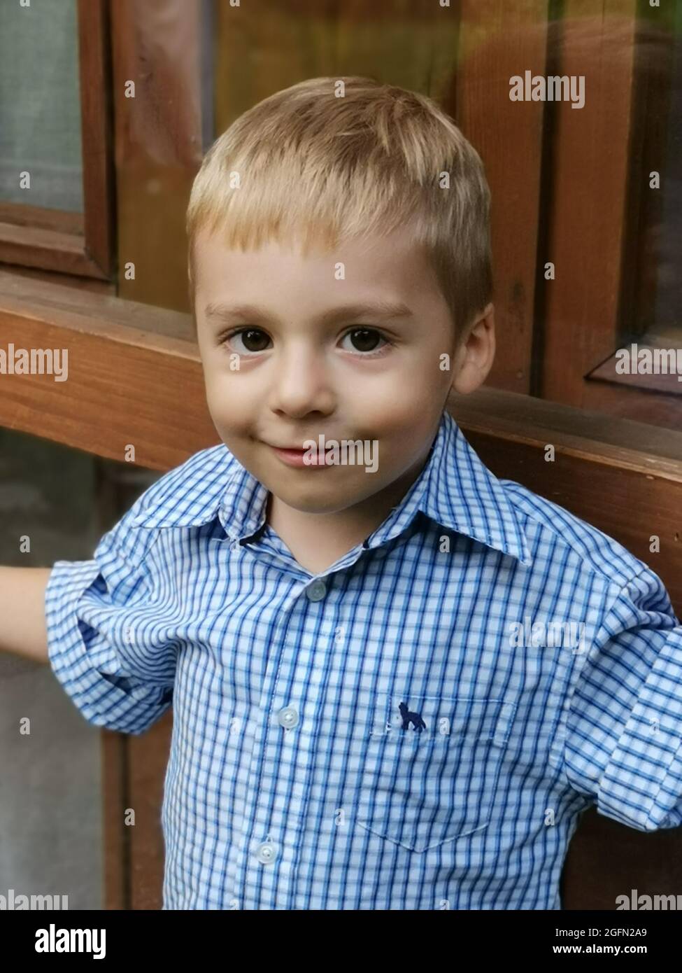Primo piano di un ragazzino sorridente con una camicia blu che guarda la fotocamera Foto Stock