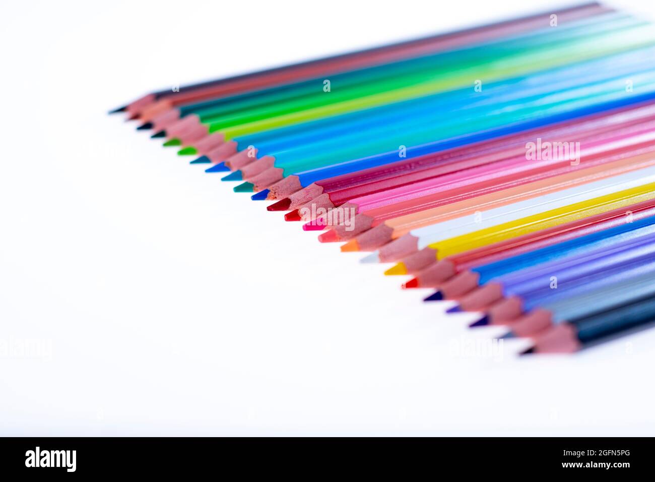24 pastelli multicolore su sfondo bianco, ordinati e affilati. Ciao scuola Foto Stock