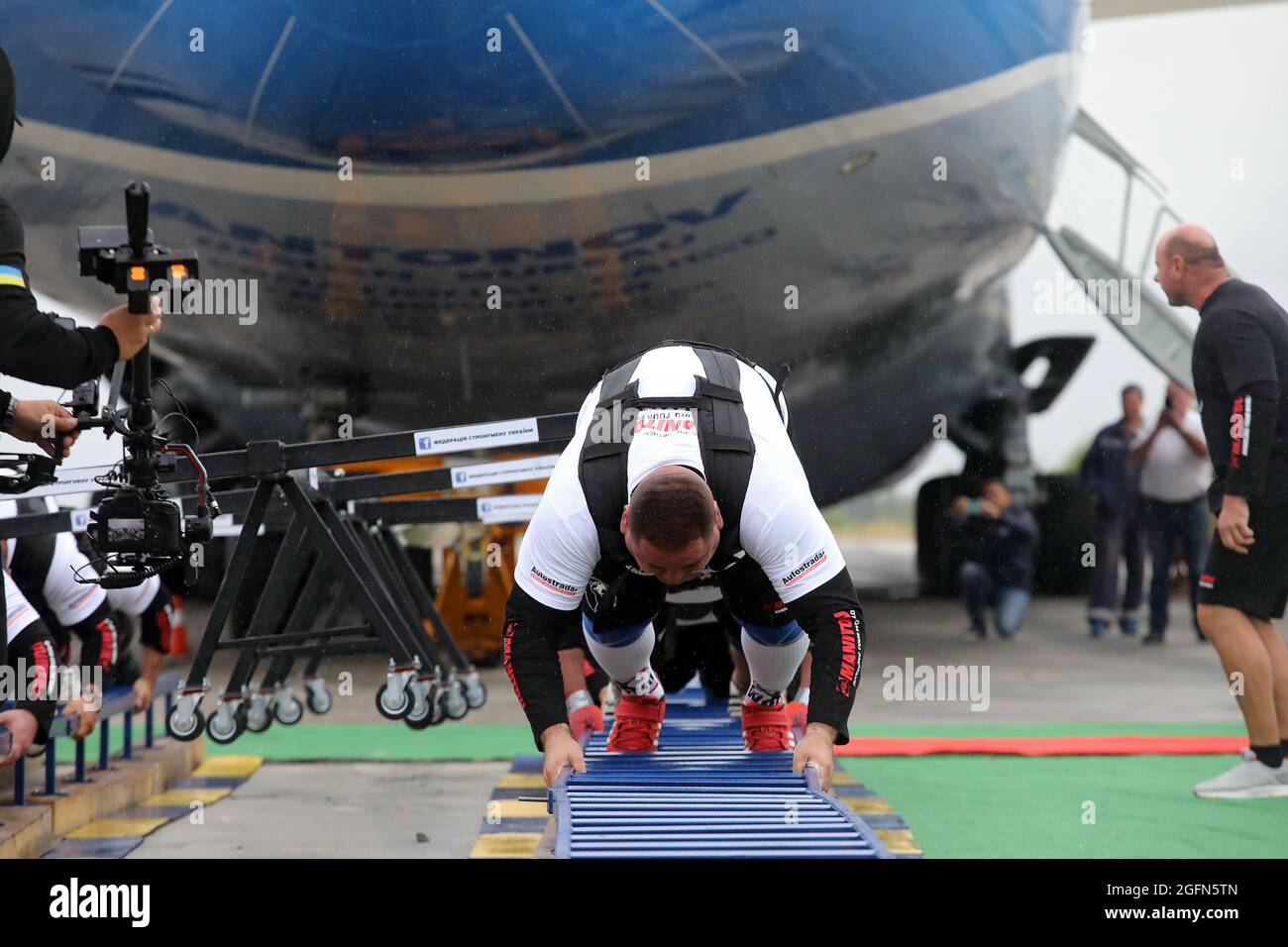 Hostomel, Ucraina. 26 agosto 2021. HOSTOMEL, UCRAINA - 26 AGOSTO 2021 - otto uomini forti sono raffigurati durante un tentativo di tirare Antonov an-225 Mriya, l'aereo più pesante mai costruito, Nel tentativo di stabilire il record per segnare 30 anni di indipendenza dell'Ucraina e il 75° anniversario della Società Antonov presso l'aerodromo Antonov, Hostomel, Regione di Kiev, Ucraina settentrionale. Gli atleti hanno tirato l'aereo 285t per quattro metri e 30 centimetri in un minuto e 13 secondi. Credit: Ukrinform/Alamy Live News Foto Stock