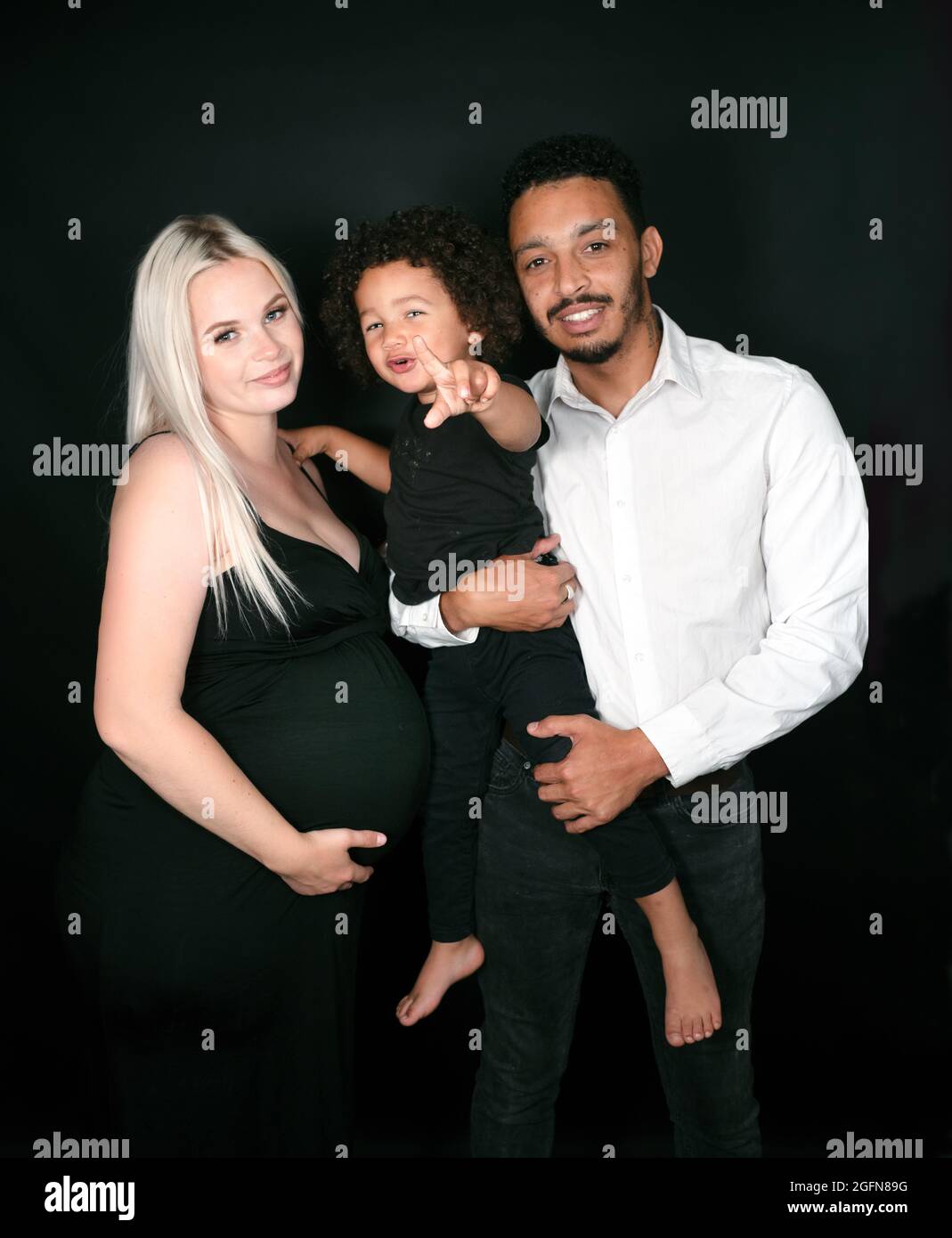 Ritratto di una famiglia multietnica elegante e felice in attesa di un bambino Foto Stock