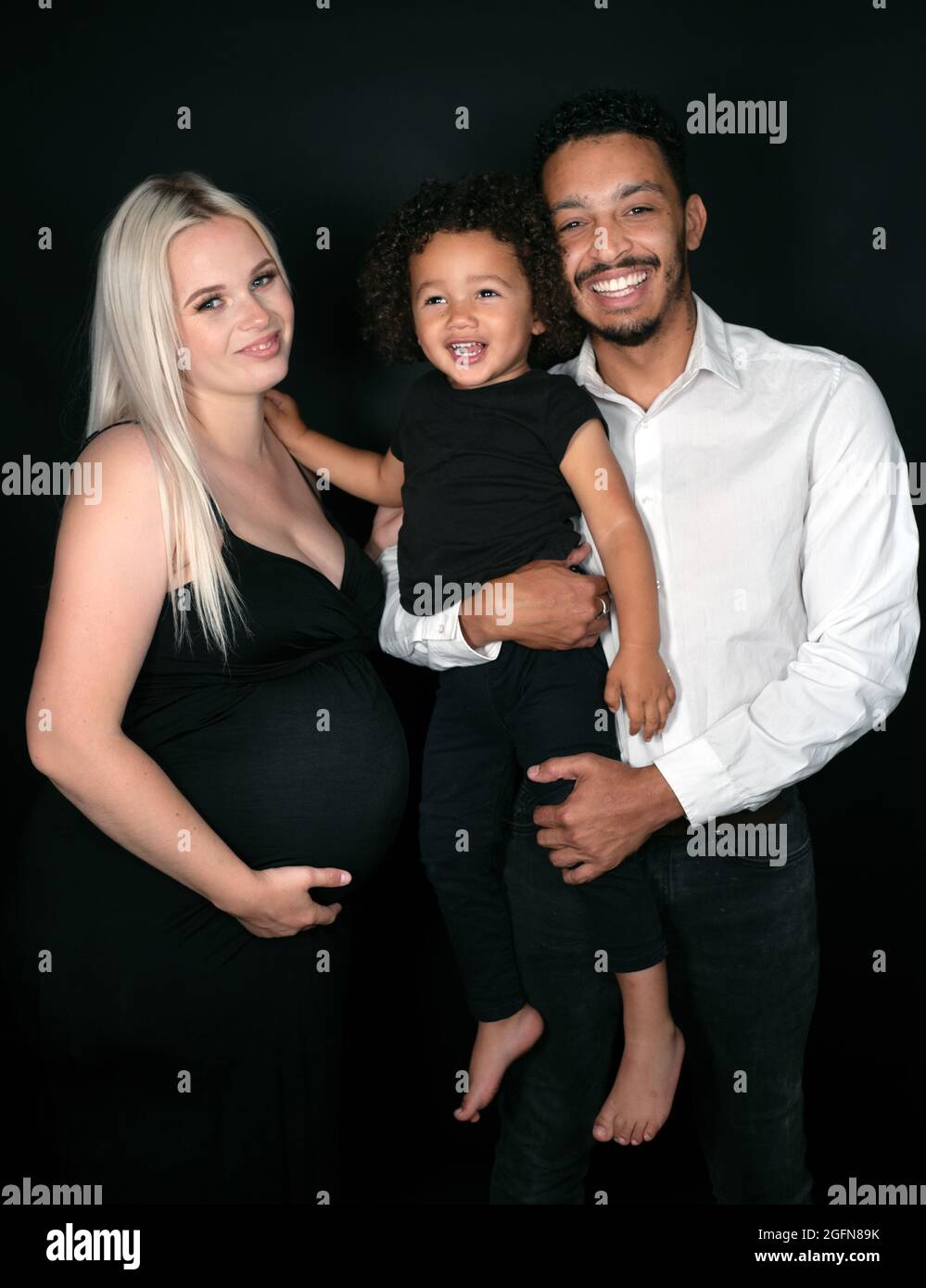 Ritratto di una famiglia multietnica elegante e felice in attesa di un bambino Foto Stock