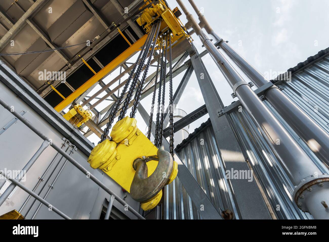 Carroponte industriale con una catena e un grande gancio giallo in fabbrica. Meccanismo di sollevamento Foto Stock