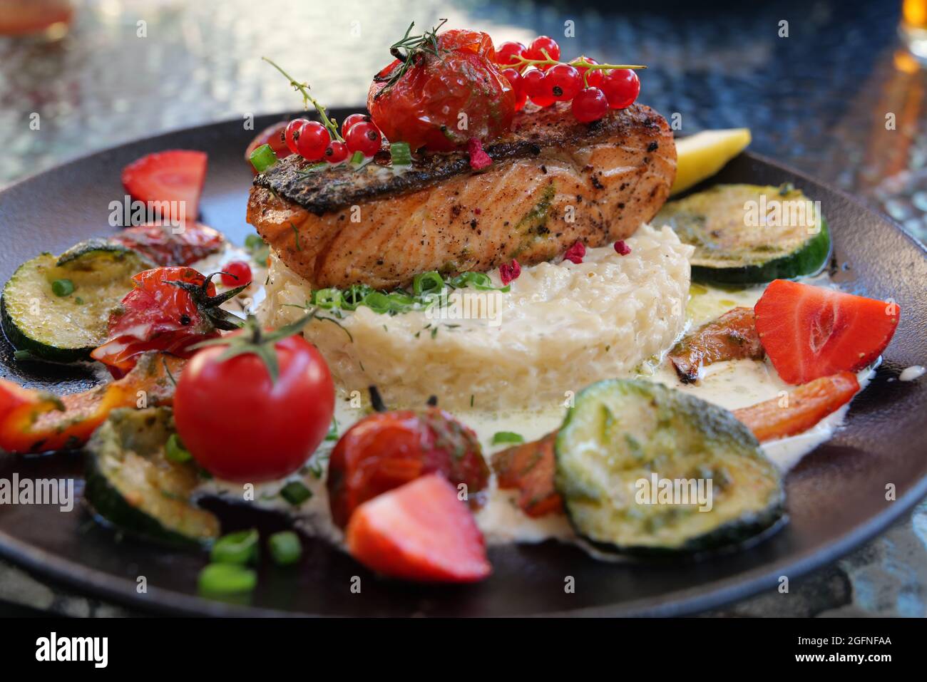 Delizioso risotto con bistecca di salmone alla griglia al forno con frutti di bosco e verdure. Cucina mediterranea, cibo sano Foto Stock