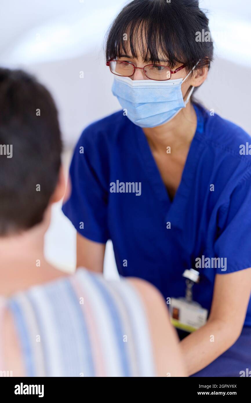 Infermiere che indossa la maschera PPE parlando con il paziente Foto Stock