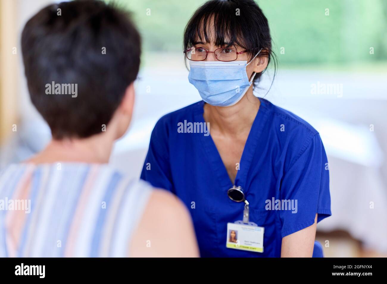 Infermiere che indossa la maschera PPE parlando con il paziente Foto Stock