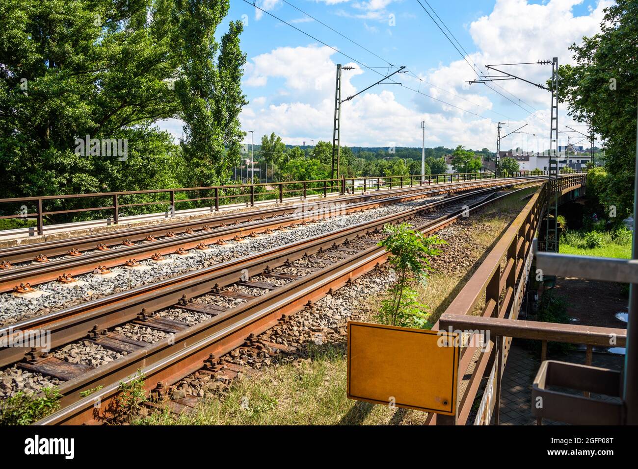 Ferrovia elettrica deserta elevata in un ambiente urbano in una soleggiata giornata estiva Foto Stock