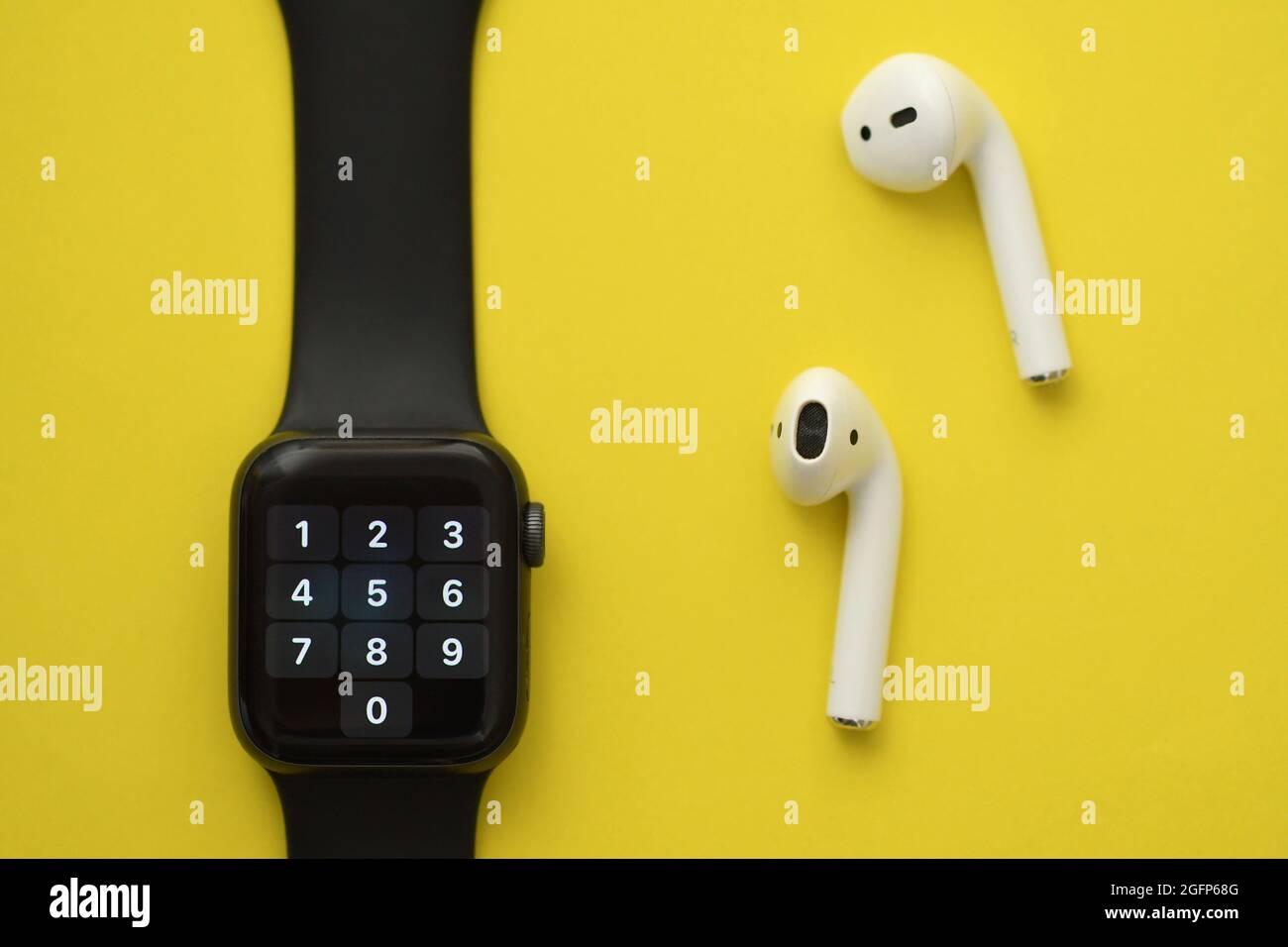 Foto degli auricolari intelligenti wireless e orologio su sfondo giallo Foto Stock