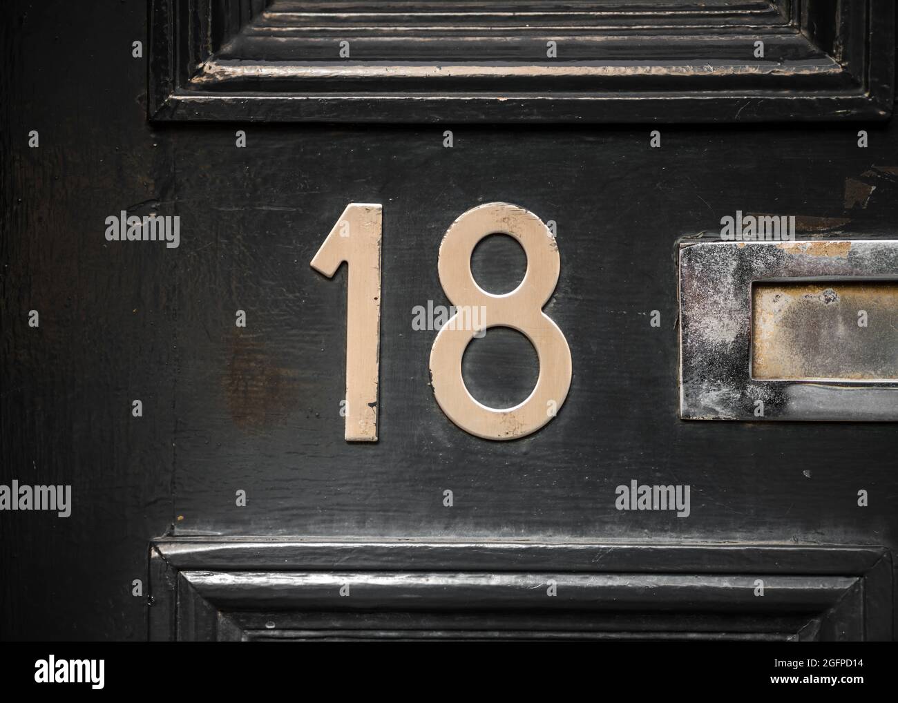 Numero 18 diciotto numeri in ottone su sportello anteriore nero lucido con letterbox visibile. Lucido e pulito. Foto Stock
