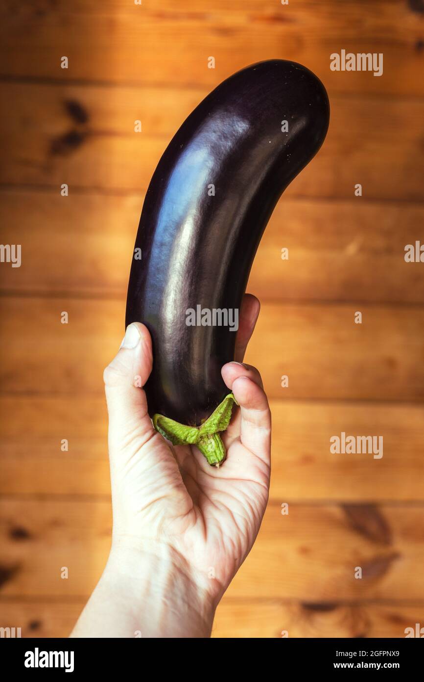 Mano con melanzane su sfondo di legno. Zdorovoye pitaniye Foto Stock