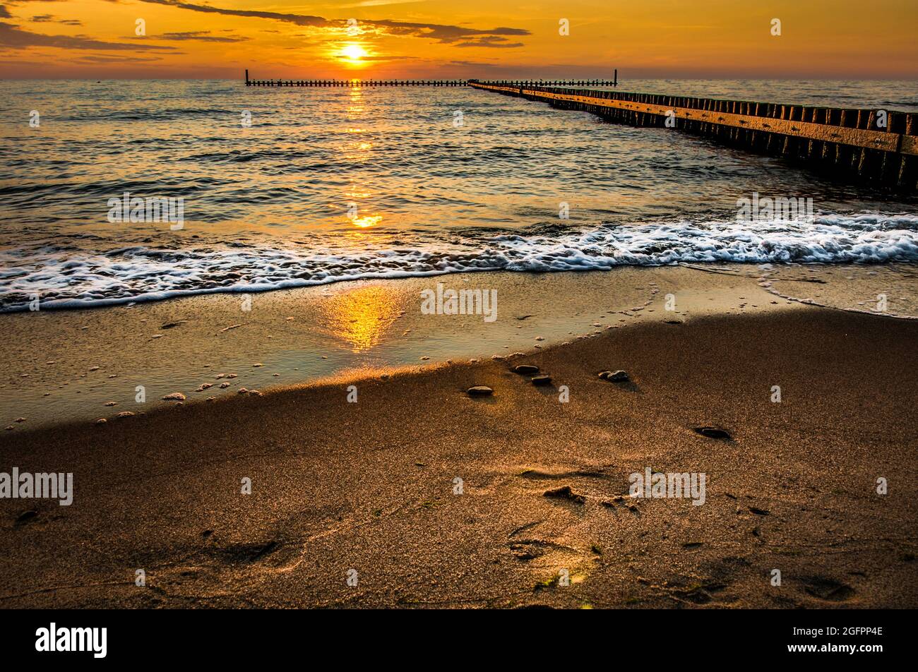 spiaggia sul mare, tramonto su un frangiflutti di legno, Mar Baltico Foto Stock
