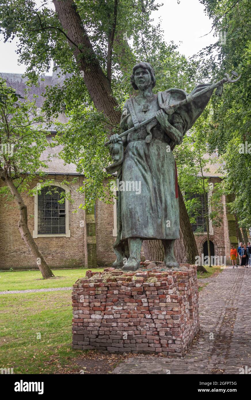 Brugge, Fiandre, Belgio - 4 agosto 2021: Cortile Beguinage. Primo piano della statua in bronzo dell'URSS della donna che detiene la bandiera con il simbolo comunista, intitolata: wh Foto Stock