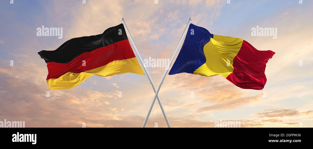 Bandiere della Germania e della romania che ondeggiano nel vento su flagelli contro il cielo con le nuvole nella giornata di sole. Simbolizzazione della relazione, dialogo tra due conti Foto Stock