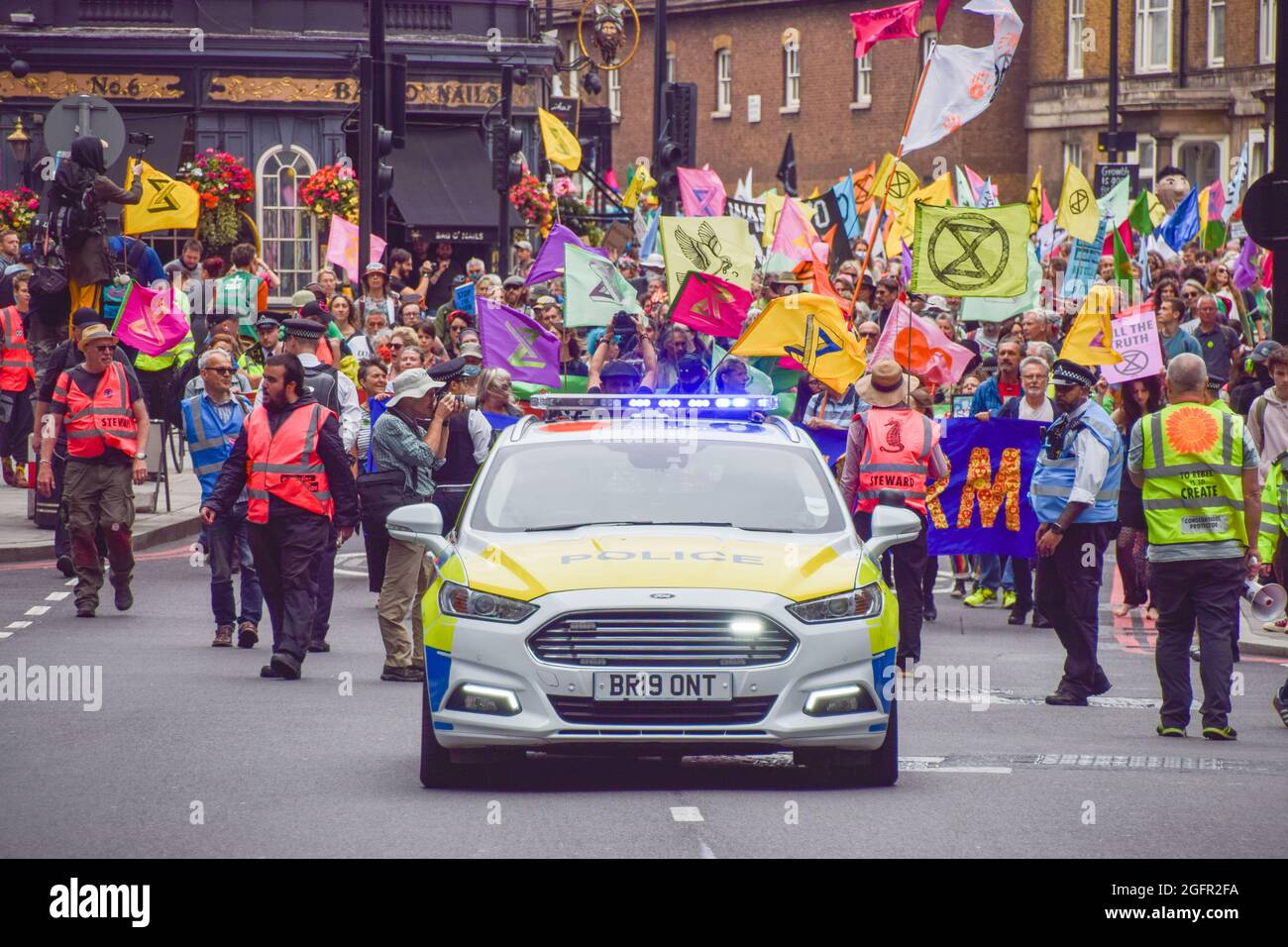 Londra, Regno Unito. 26 agosto 2021. Una macchina di polizia guida di fronte ai manifestanti che marciarono a Victoria durante la manifestazione. I manifestanti della ribellione di estinzione marciarono da Hyde Park al Dipartimento per le imprese, l'energia e la strategia industriale come parte della loro campagna di due settimane, la ribellione impossibile, Esortare il governo britannico ad agire in modo significativo sulla crisi climatica ed ecologica. Credit: SOPA Images Limited/Alamy Live News Foto Stock