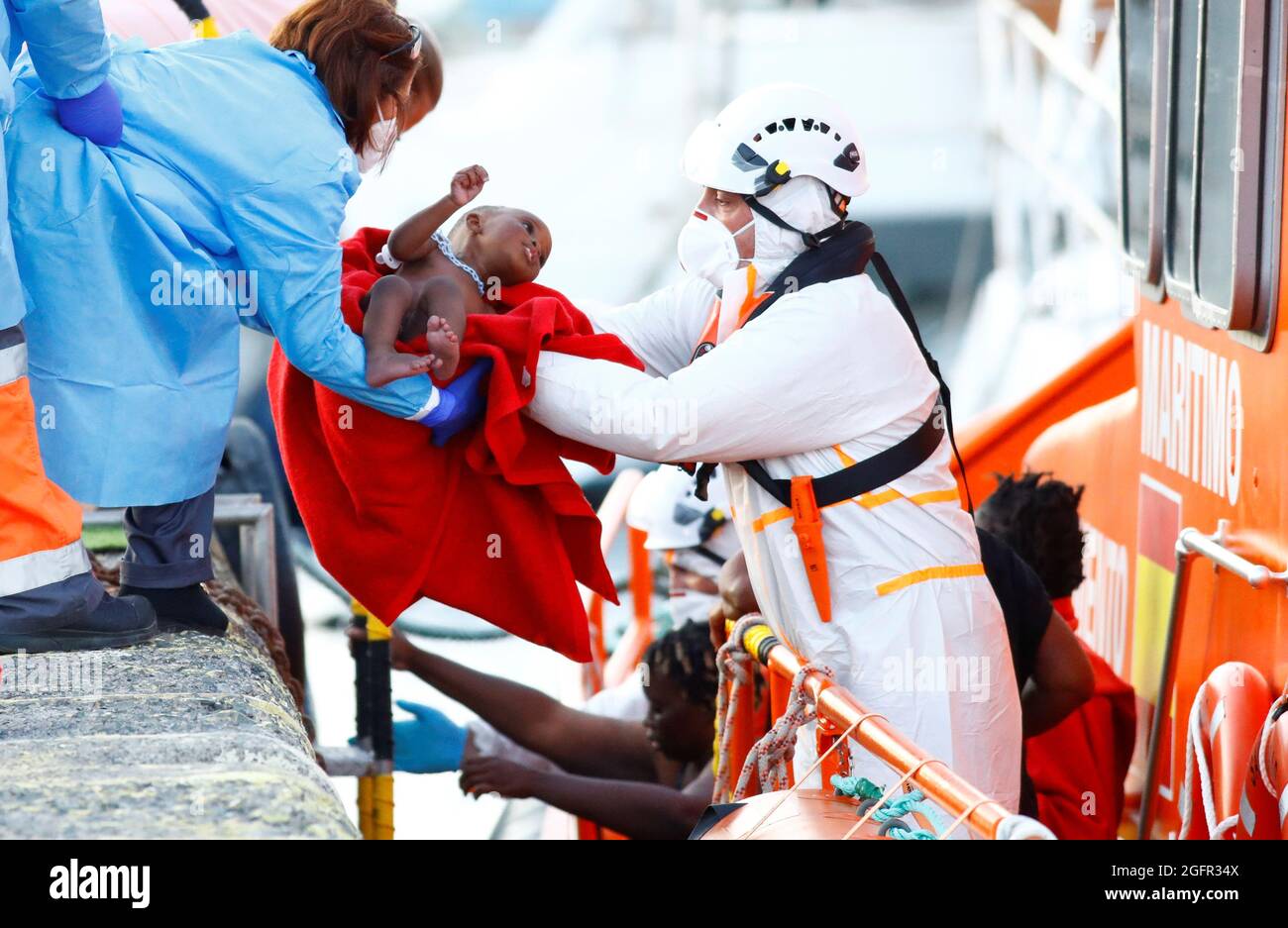 I soccorritori aiutano un bambino migrante a sbarcare da una nave di guardia costiera spagnola, nel porto di Arguineguin, nell'isola di Gran Canaria, Spagna, 26 agosto 2021. REUTERS/Borja Suarez Foto Stock